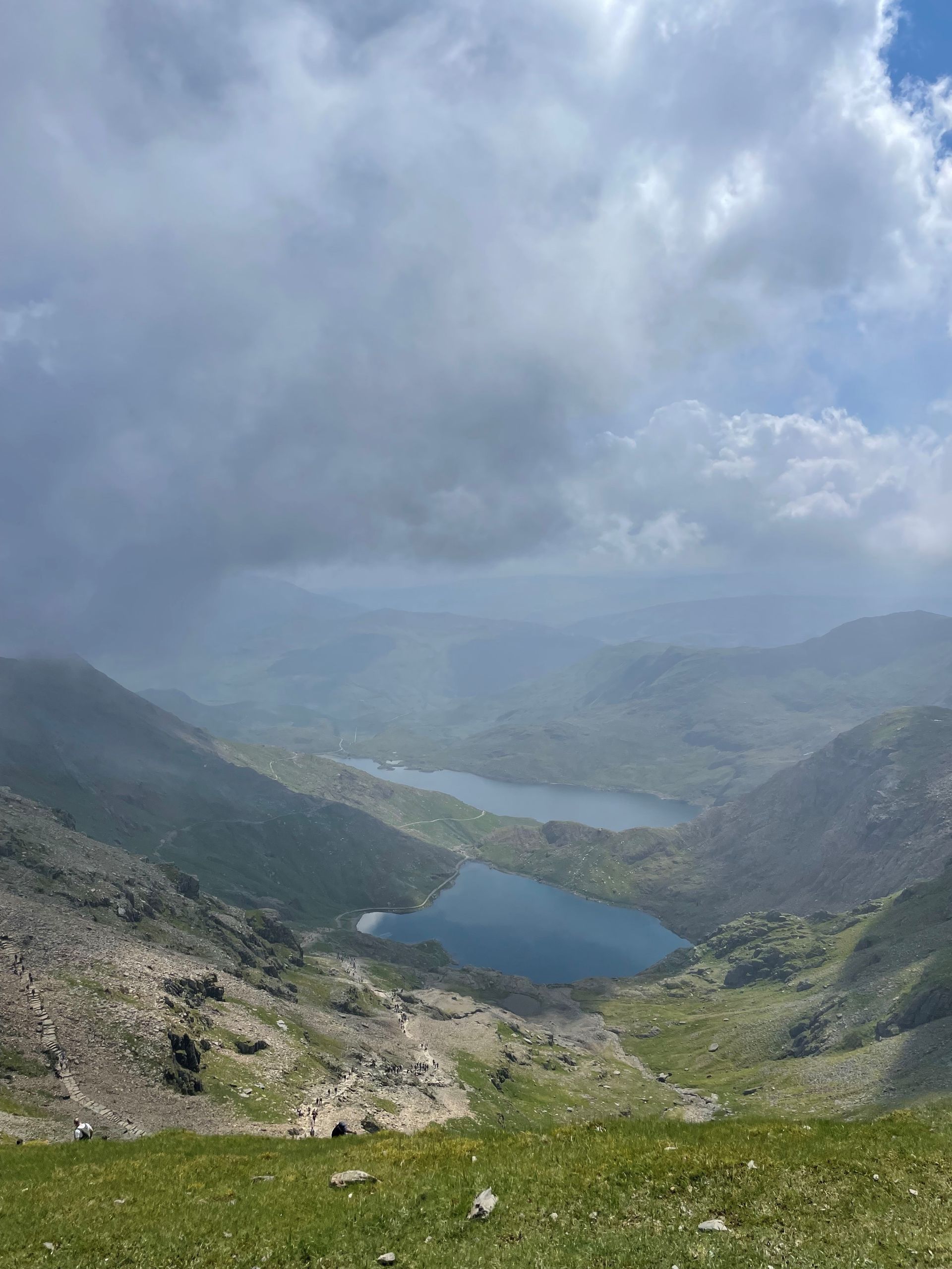 A view of a lake surrounded by mountains on a cloudy day.