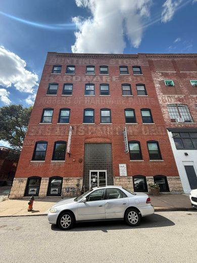 Red brick building with arched windows, a white car parked in front.