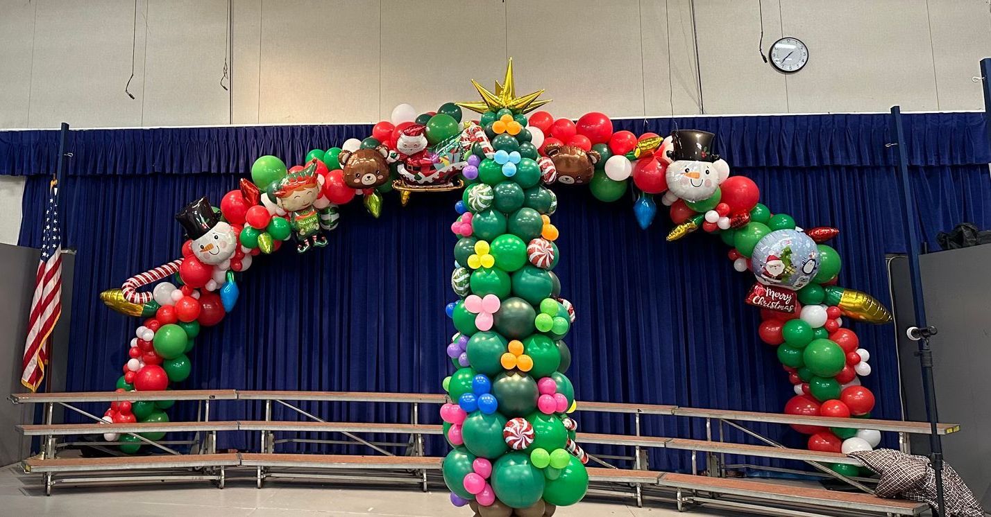 Christmas-themed balloon arch with a central tree and festive decorations.