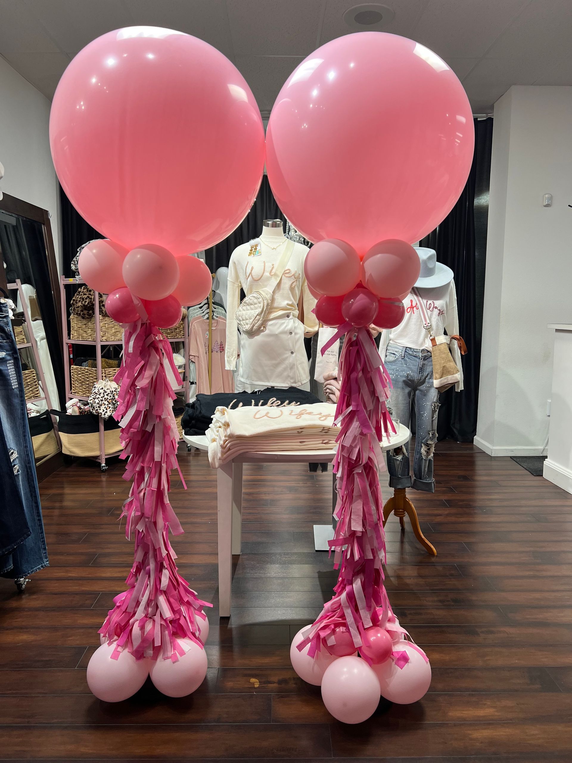 Two pink balloon columns decorated for an event, standing inside a store.