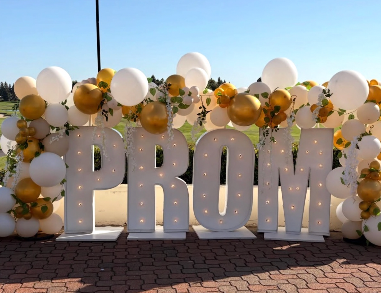 PROM marquee letters with elegant white and gold balloon garland.