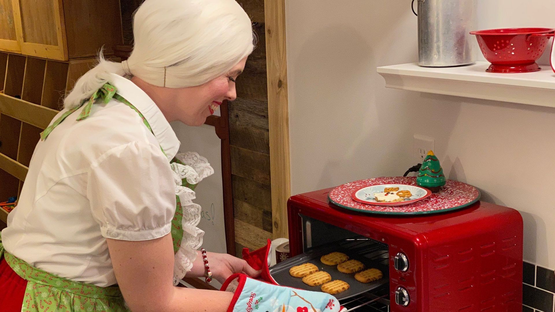 A woman is putting cookies in a red oven.
