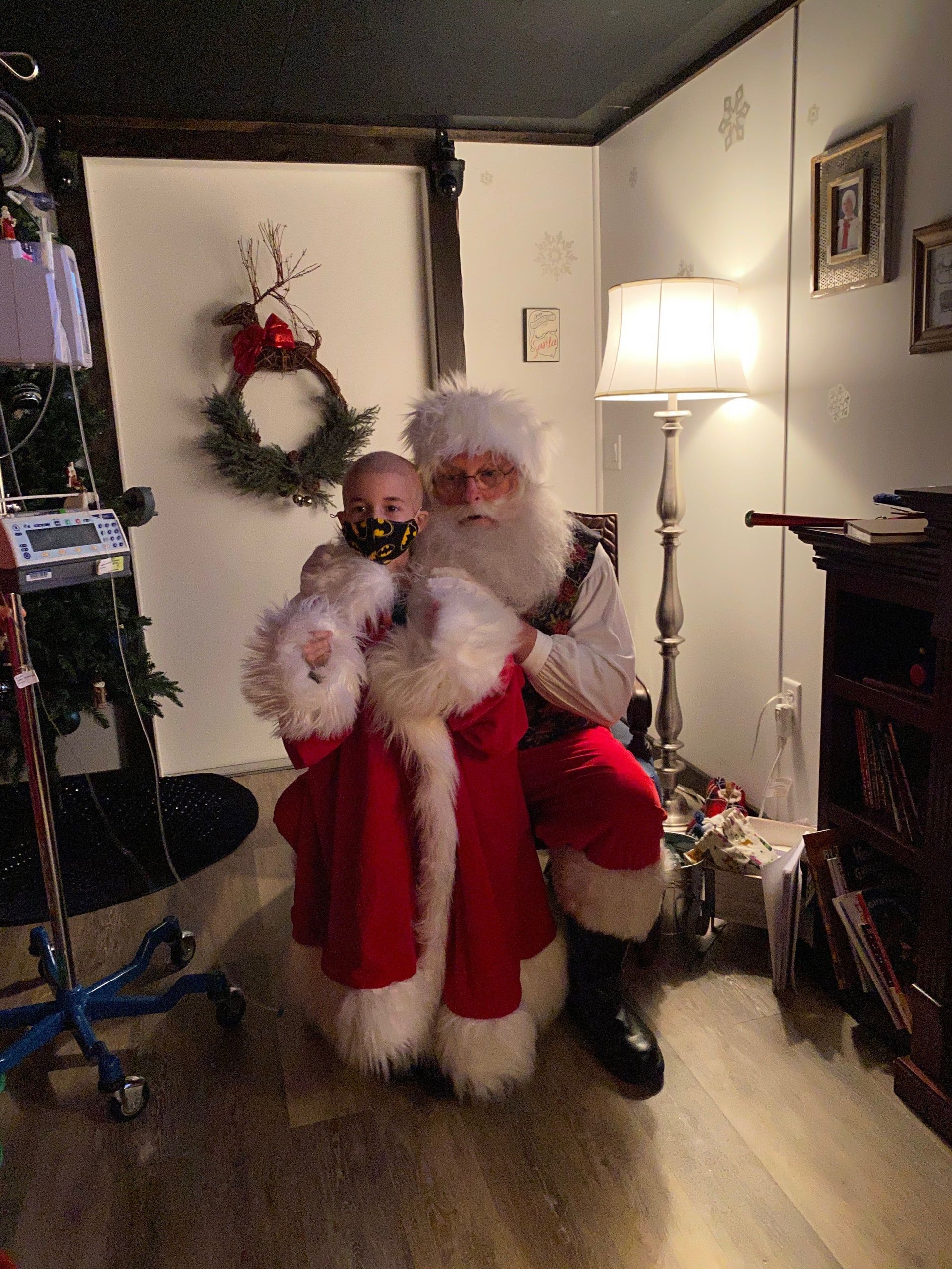 A man dressed as santa claus is holding a baby in a room.