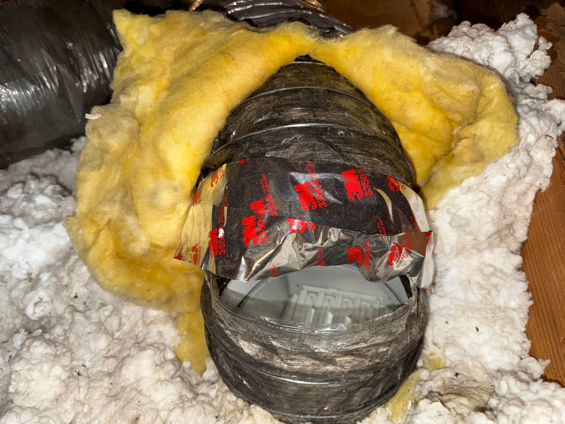 Close-up of a taped cylindrical object wrapped in insulation foam with red markings inside a pipe opening