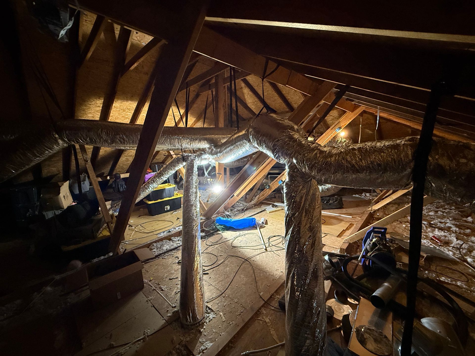 Collapsed wooden attic with debris, beams, and a bright work light illuminating the damage
