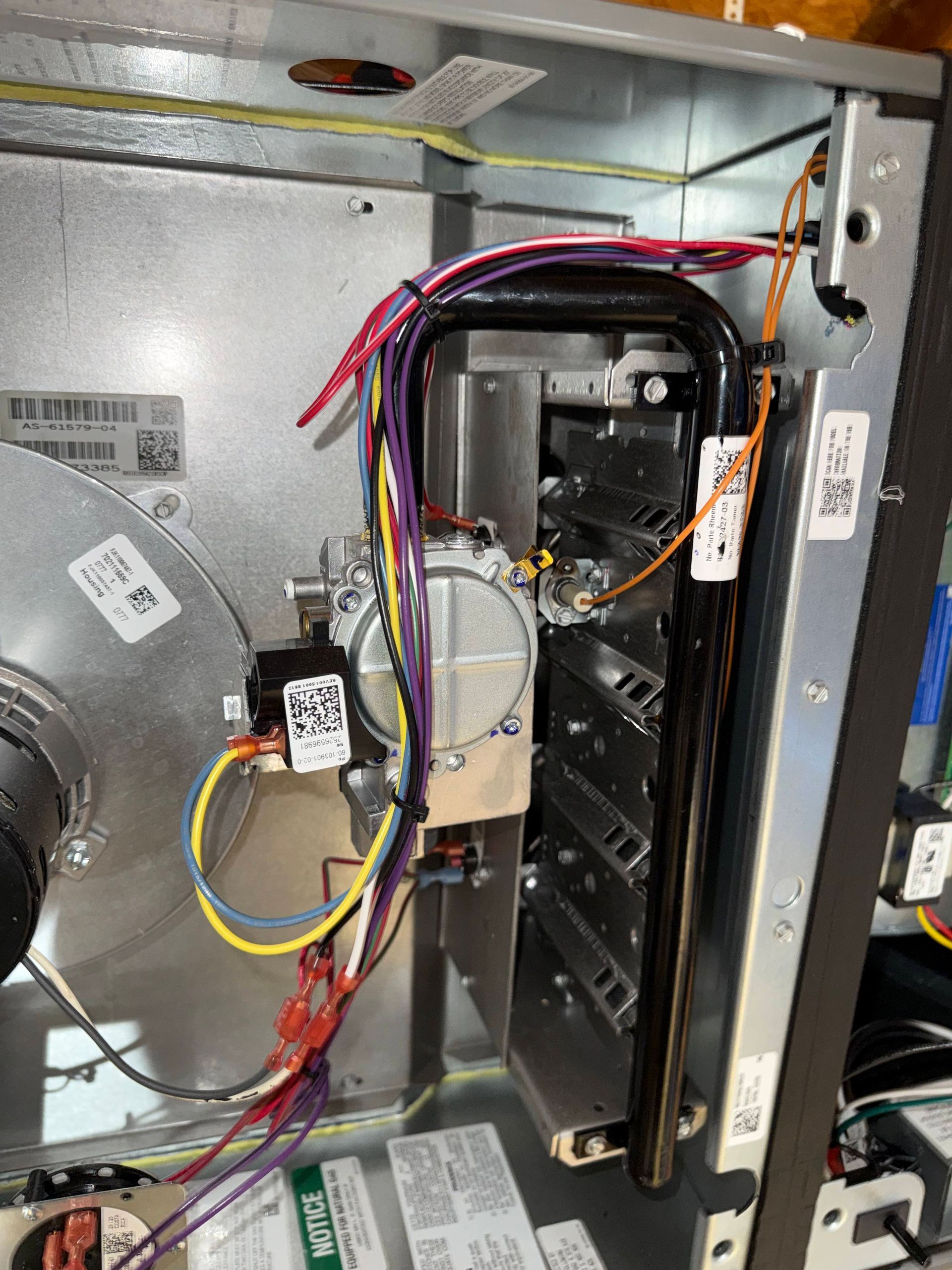 Interior of an HVAC unit with wiring, a control module, and metal components exposed.