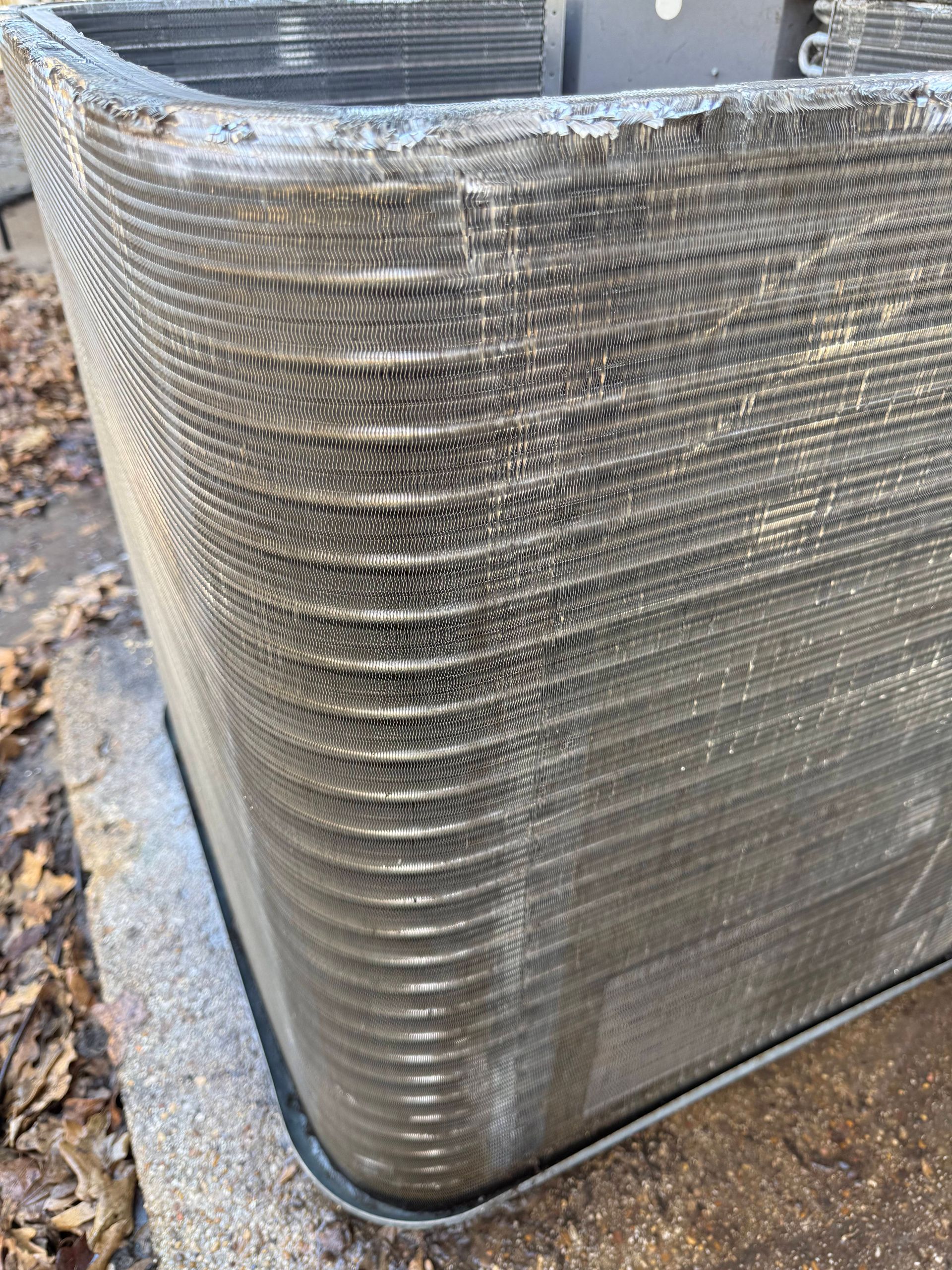 Stacked silver metal trays or pans wrapped in plastic on a pallet outdoors.