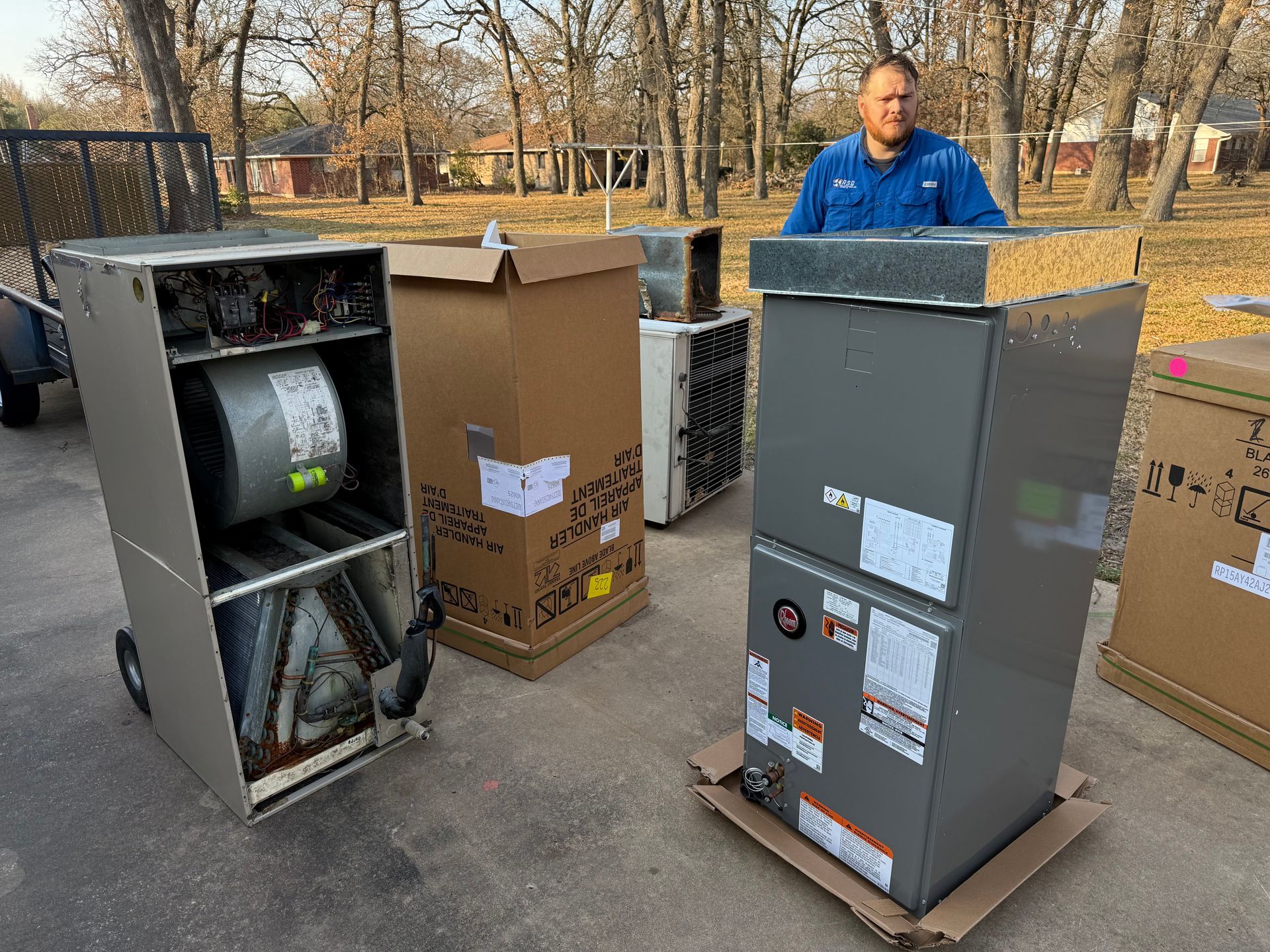 Two open metal cabinets on cardboard boxes outdoors, with a man in a blue jacket in the background