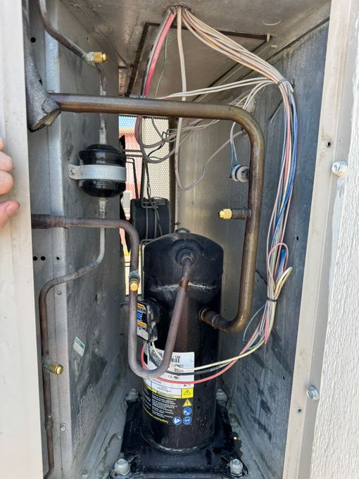 Open HVAC closet with compressor, copper lines, wires, and metal piping visible