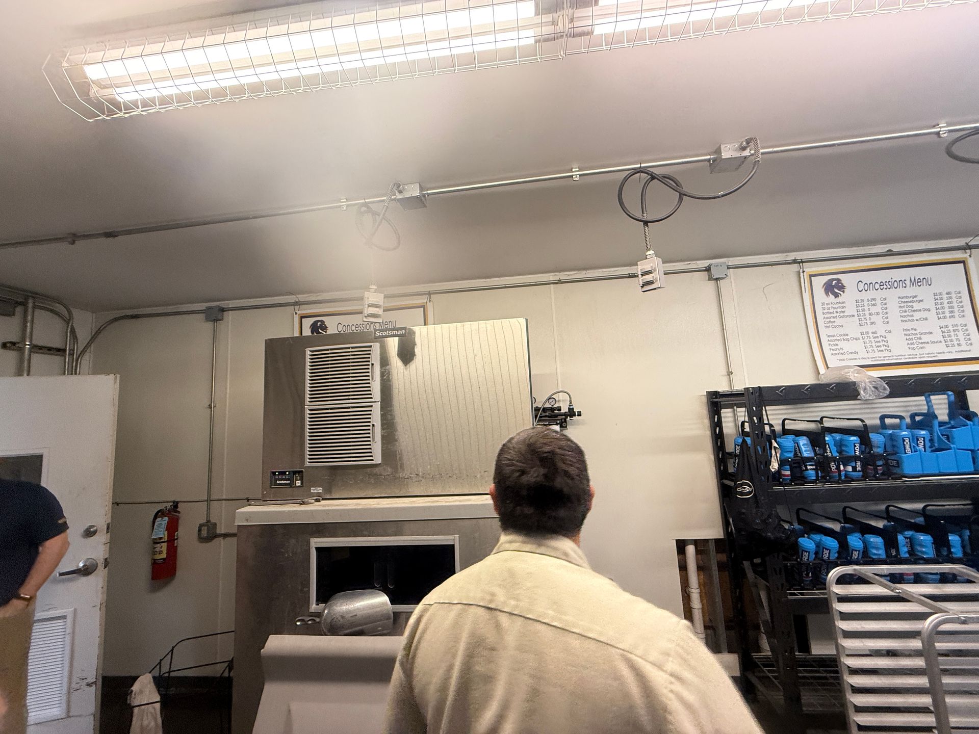 Baker in a kitchen facing an industrial oven, with metal racks and prep equipment around the room.