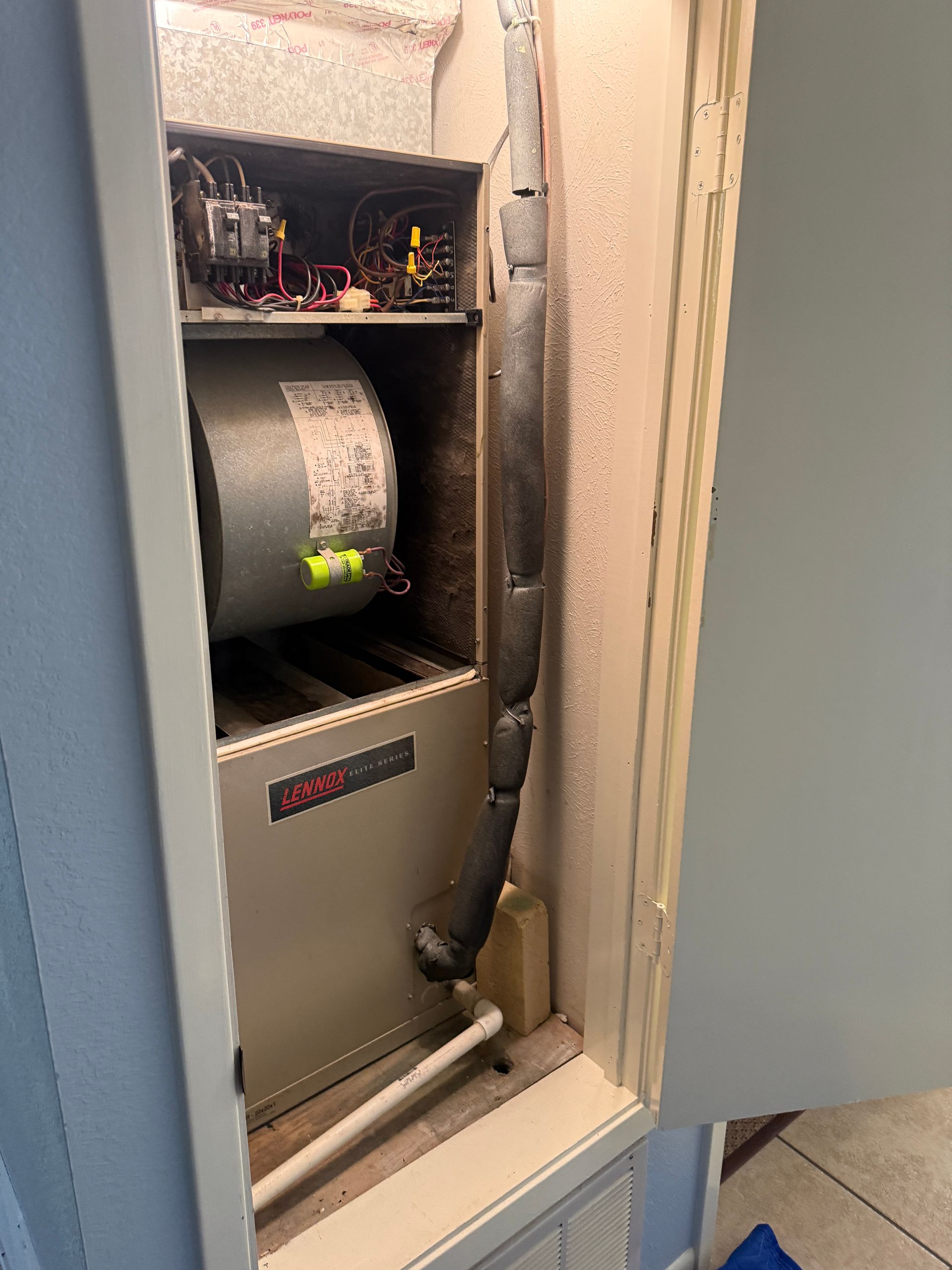 Open electrical panel with wiring, large coil, and gray equipment inside a narrow cabinet.
