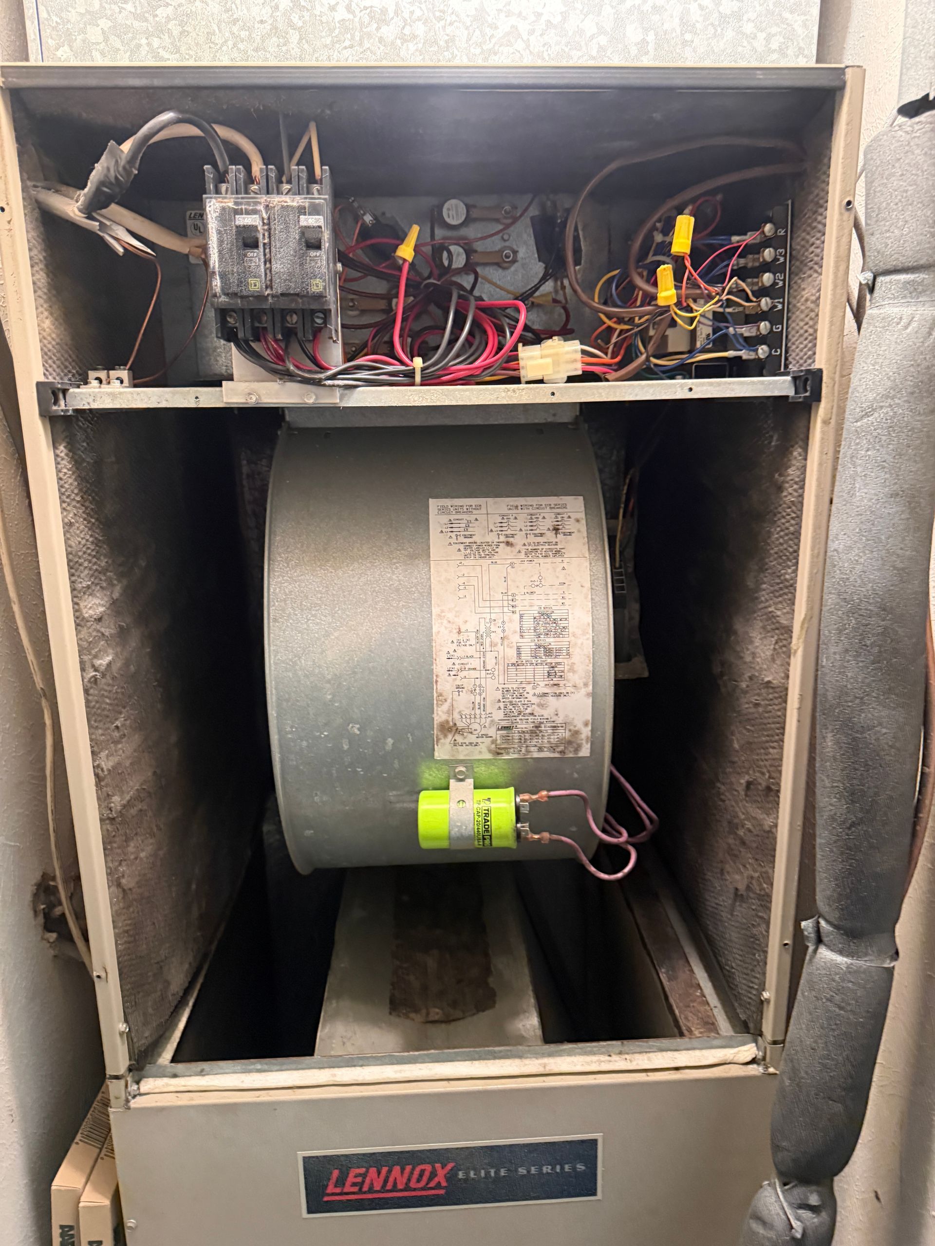 Open HVAC furnace cabinet with exposed wiring and blower motor inside.