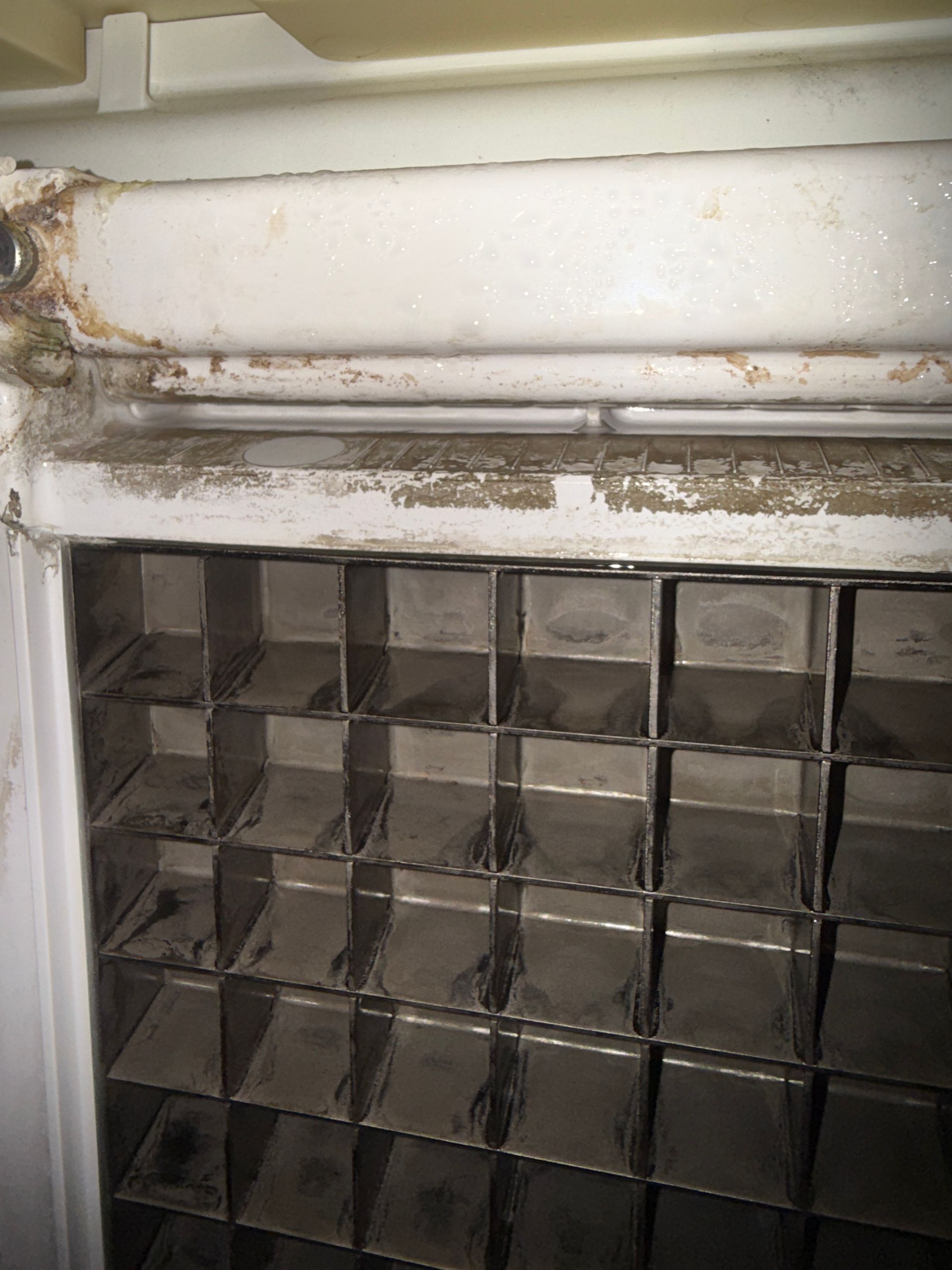 Close-up of a dirty glass block wall under a damaged white ledge with peeling paint and grime