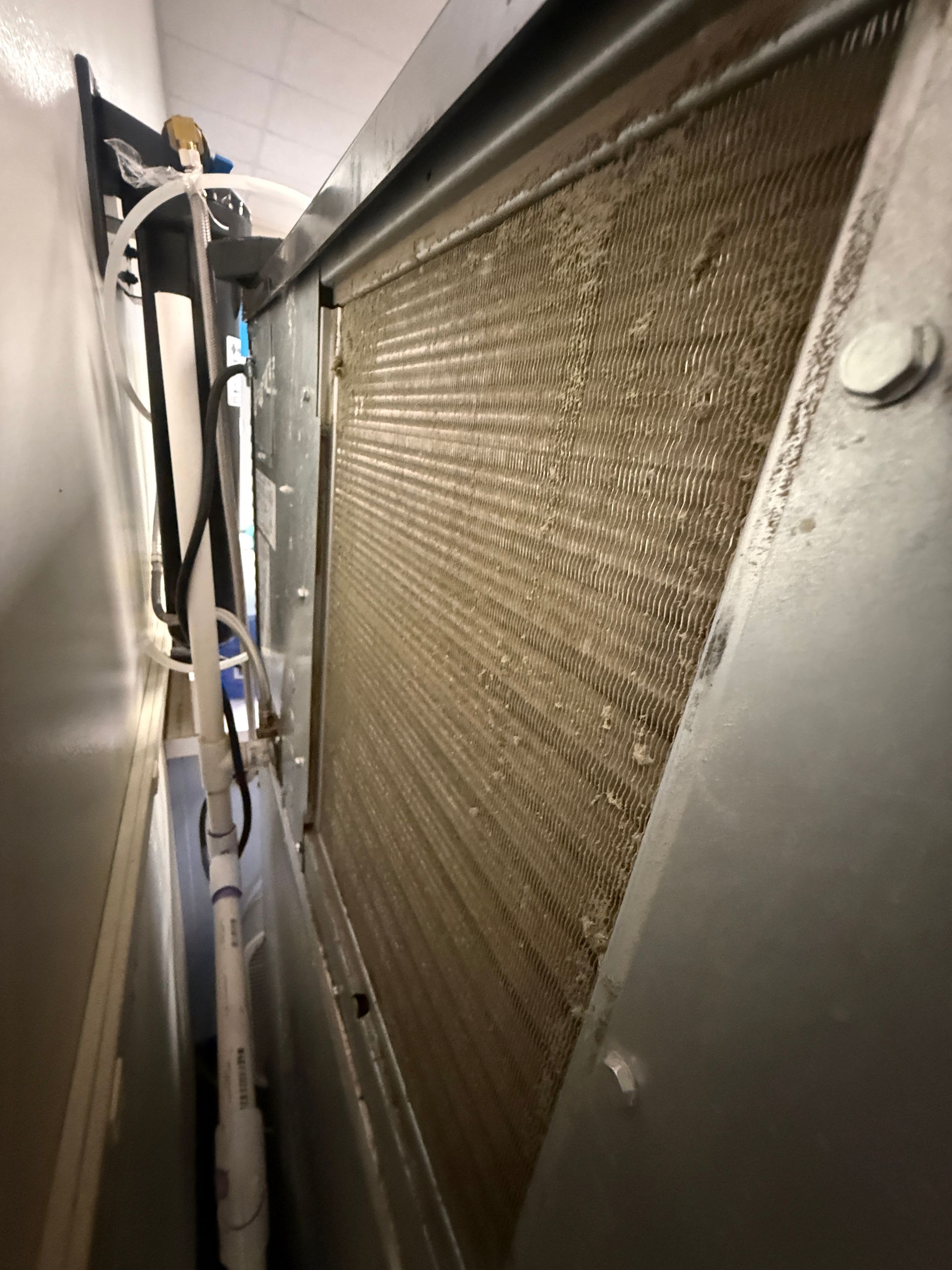 Close-up of a narrow metal corridor with a large textured panel and exposed cables.