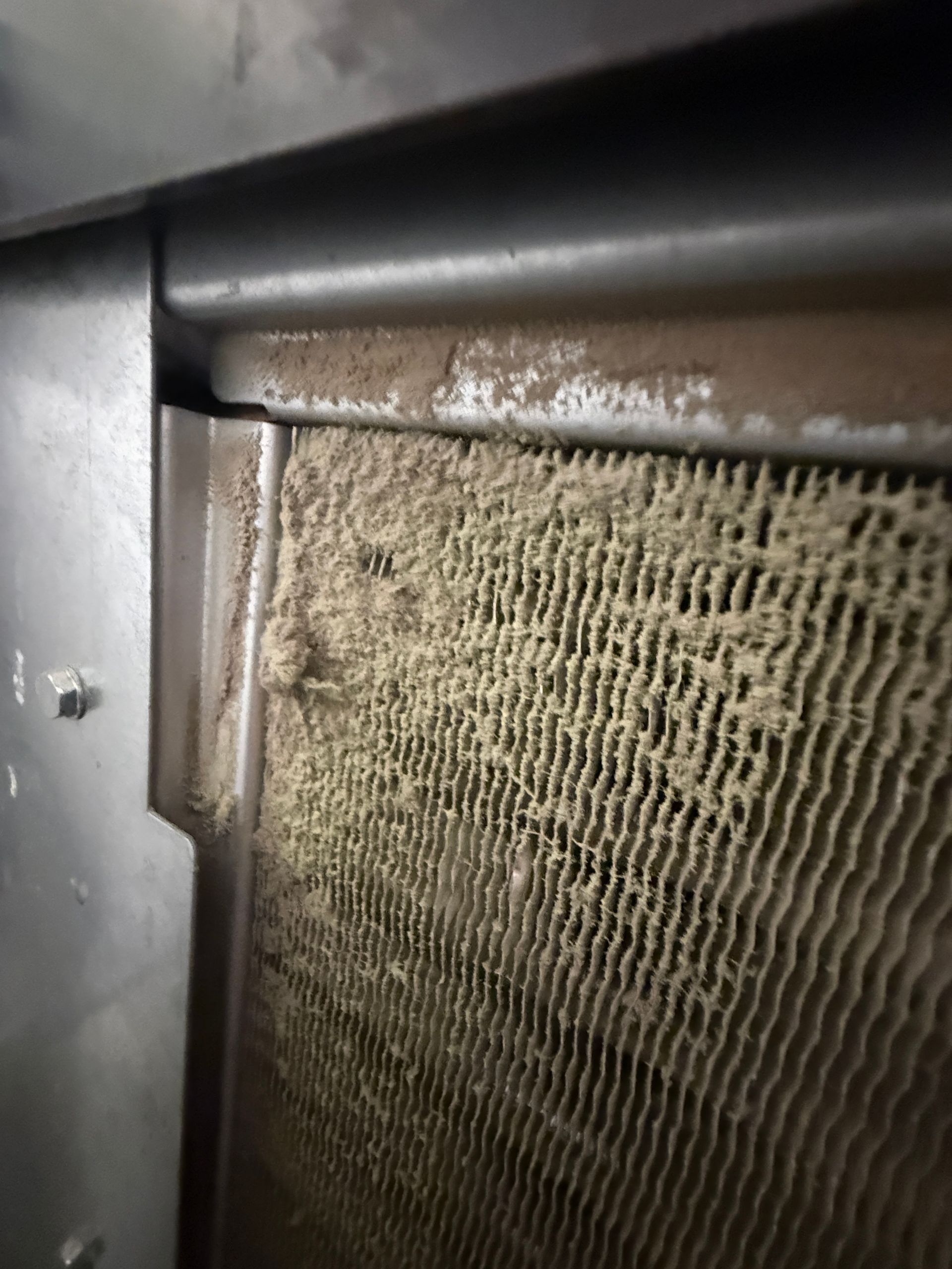 Dirty, worn furnace or air filter with dust buildup on a metal frame