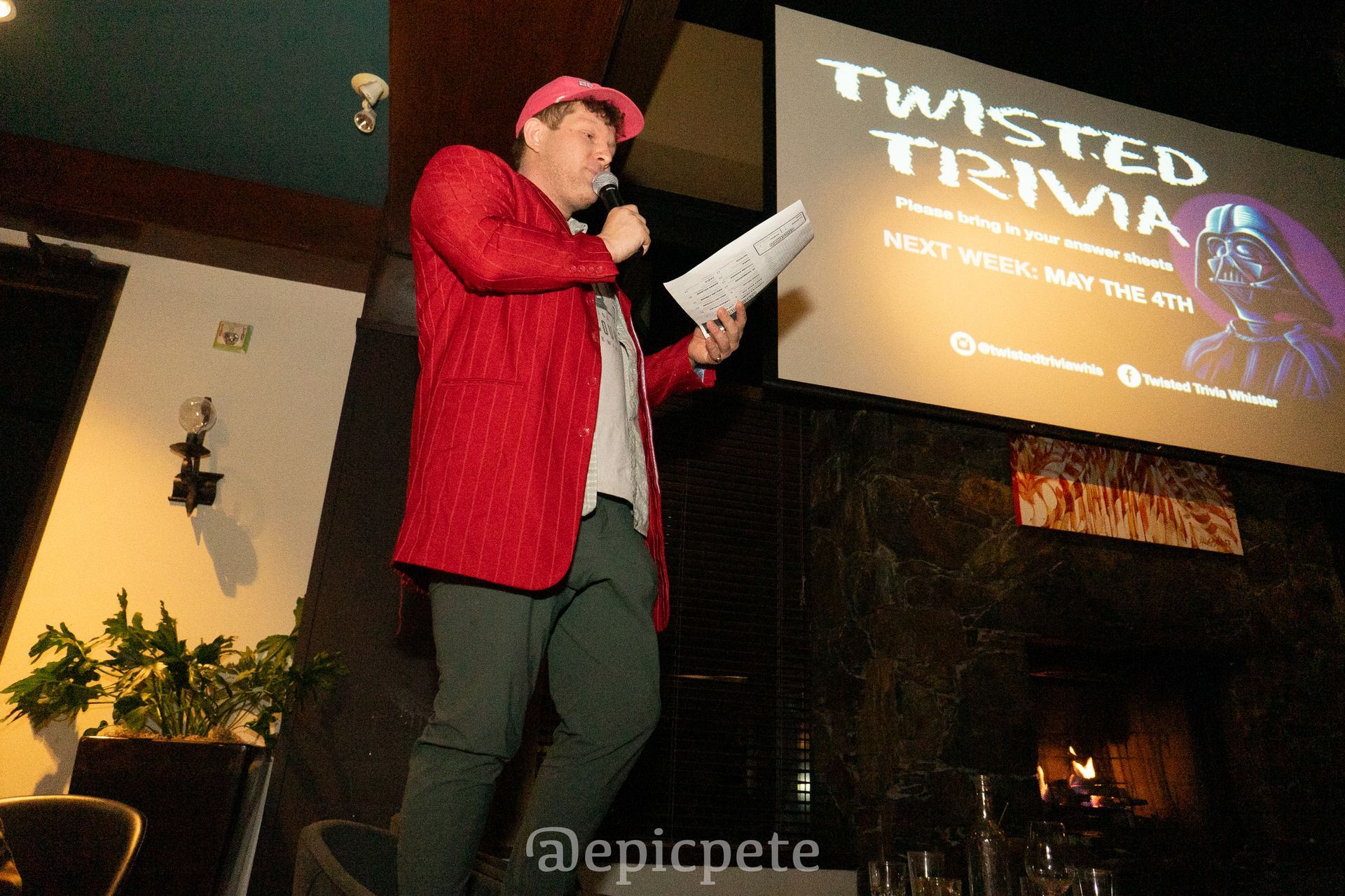A man is standing in front of a screen that says twisted trivia