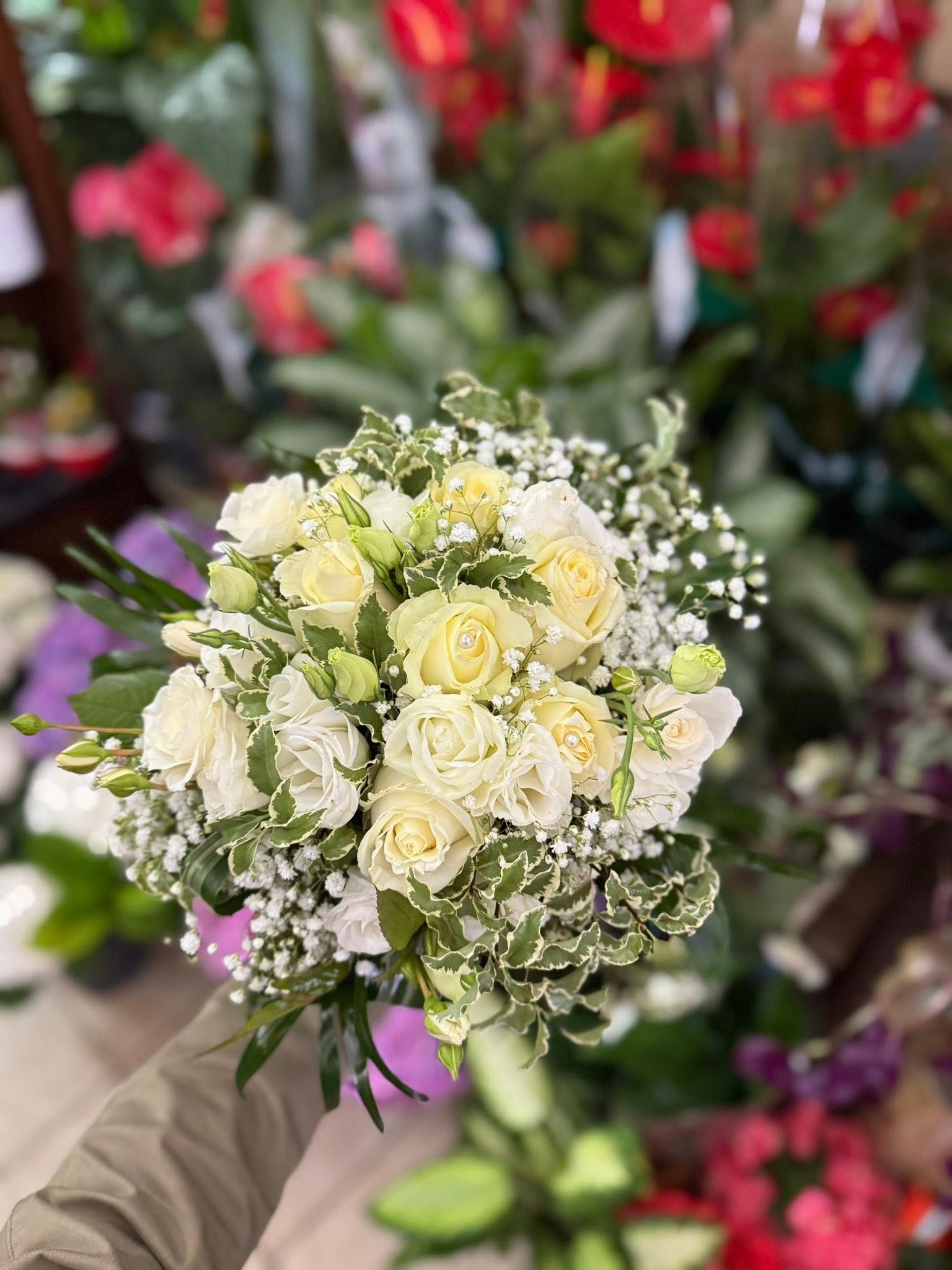 Bouquet di rose bianche e verde, su uno sfondo floreale sfocato.