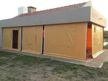 Pequeña estructura cubierta de color tostado, con techo gris y puerta abierta