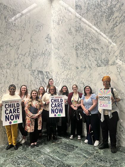 A group of people are standing next to each other holding signs that say `` child care now ''.