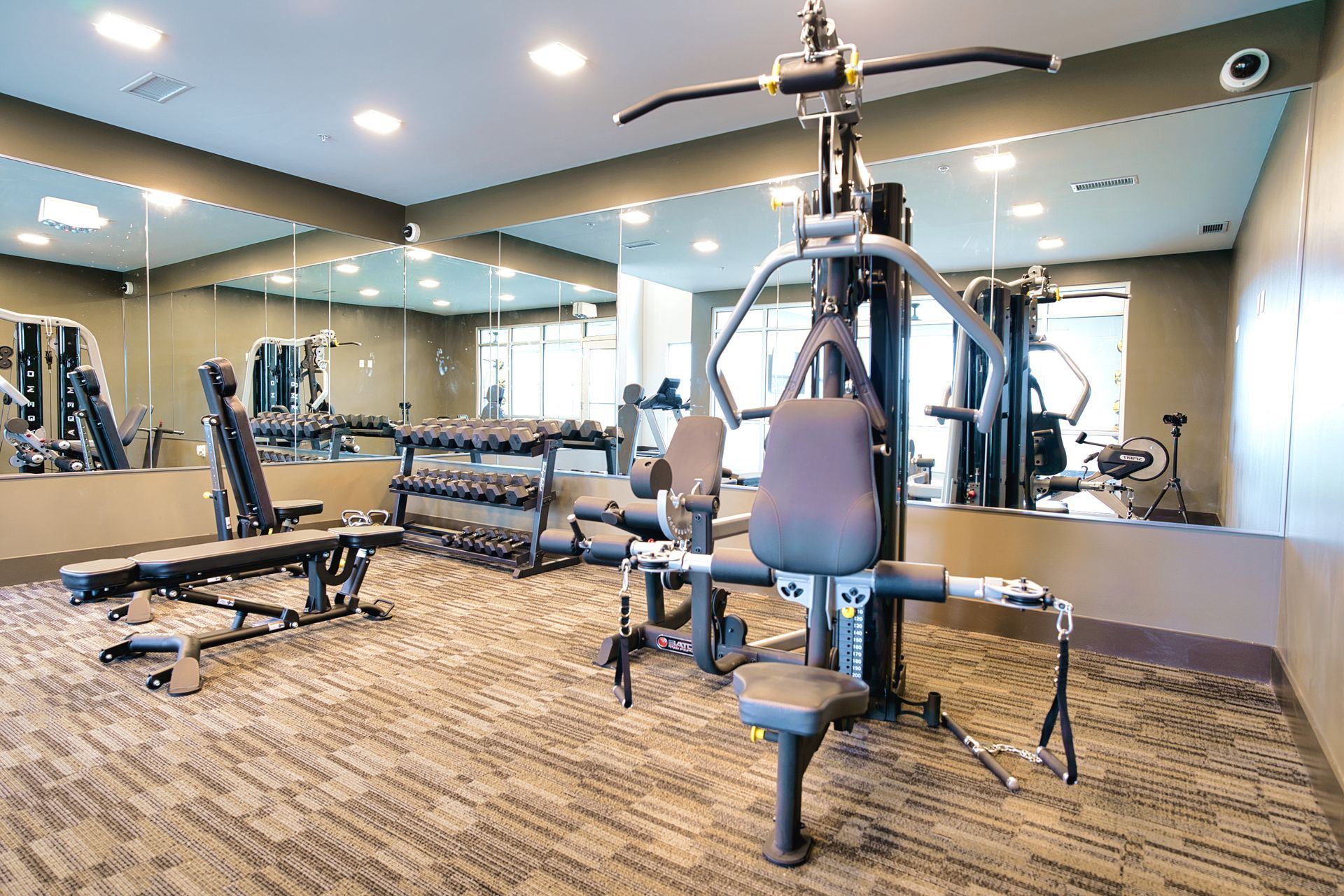 A gym filled with lots of exercise equipment and mirrors.