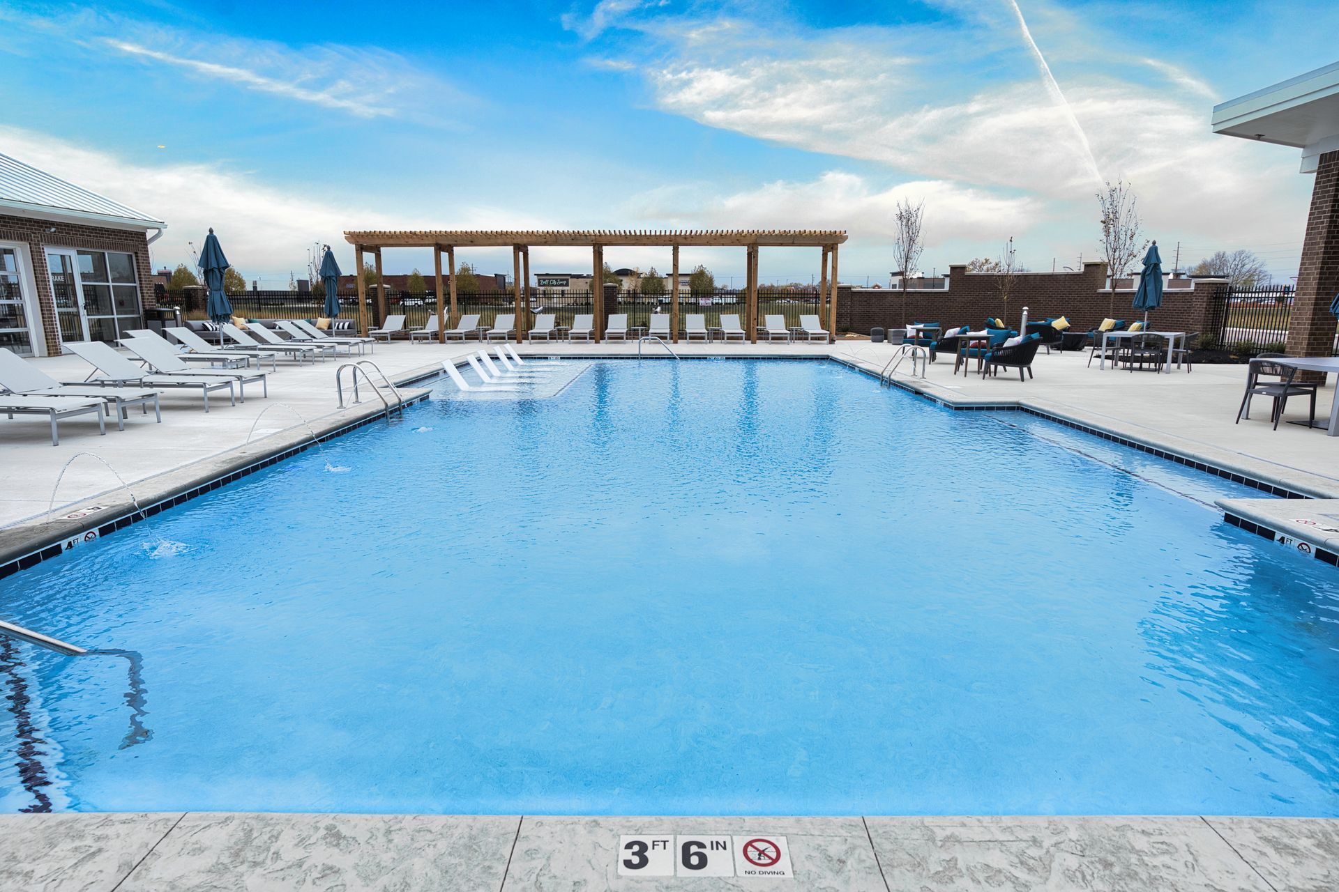 A large swimming pool with chairs and umbrellas around it.