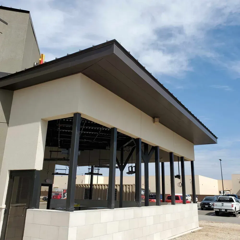 Exterior of a modern white building with a dark roof and open windows under a blue sky