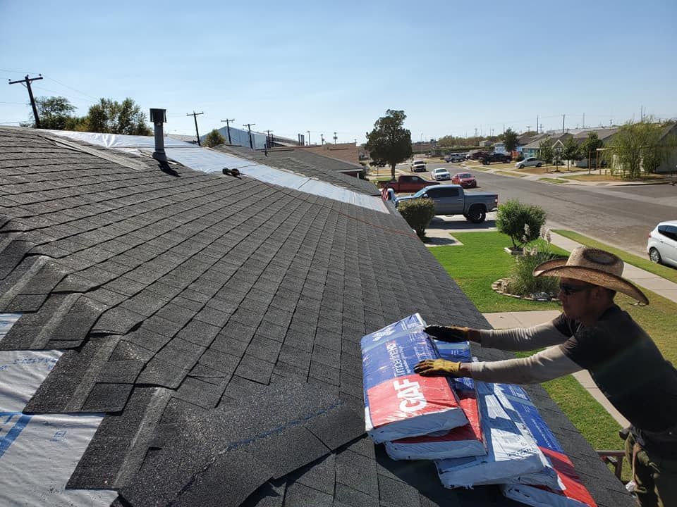Worker on a roof installing shingles beside a suburban street