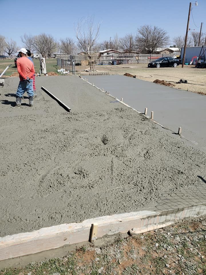 Construction worker spreading concrete on a sidewalk slab outdoors in a residential area