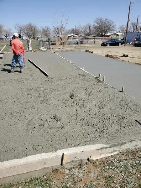 Fresh concrete being poured and leveled on a residential street construction site