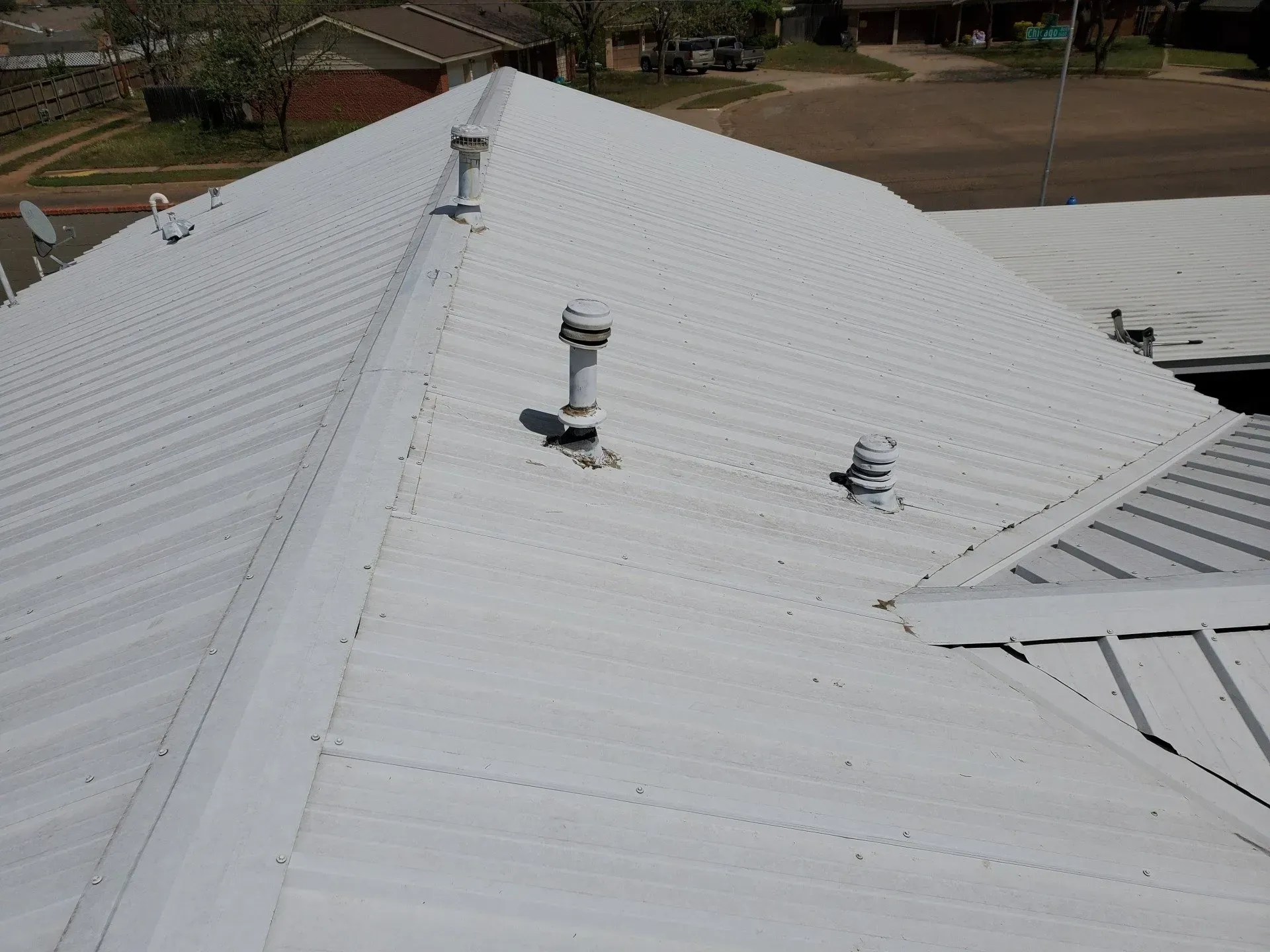 White metal roof with several vents and a sloped ridge, viewed from above