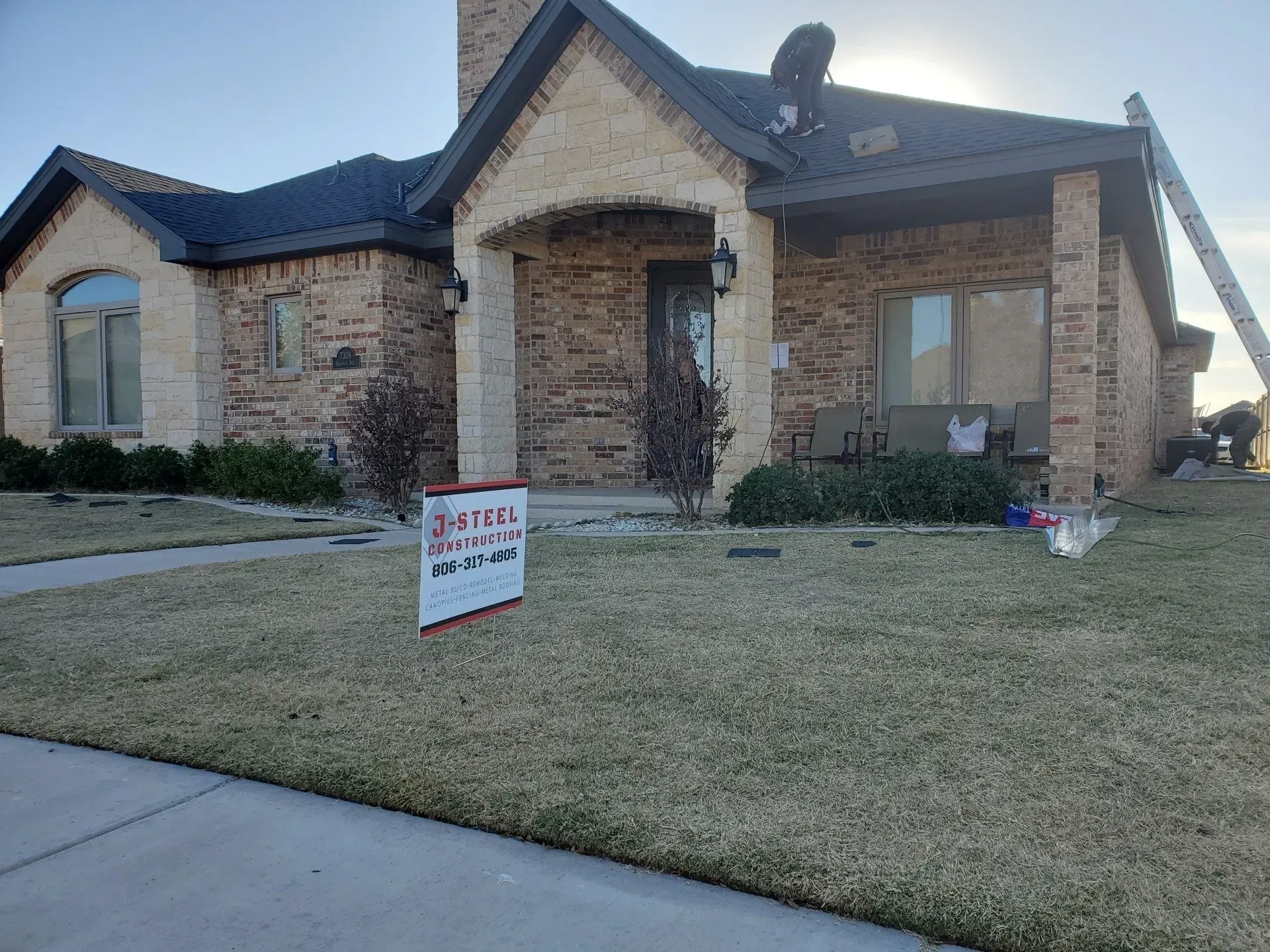 Brick house with a front lawn and a real estate sign by the driveway
