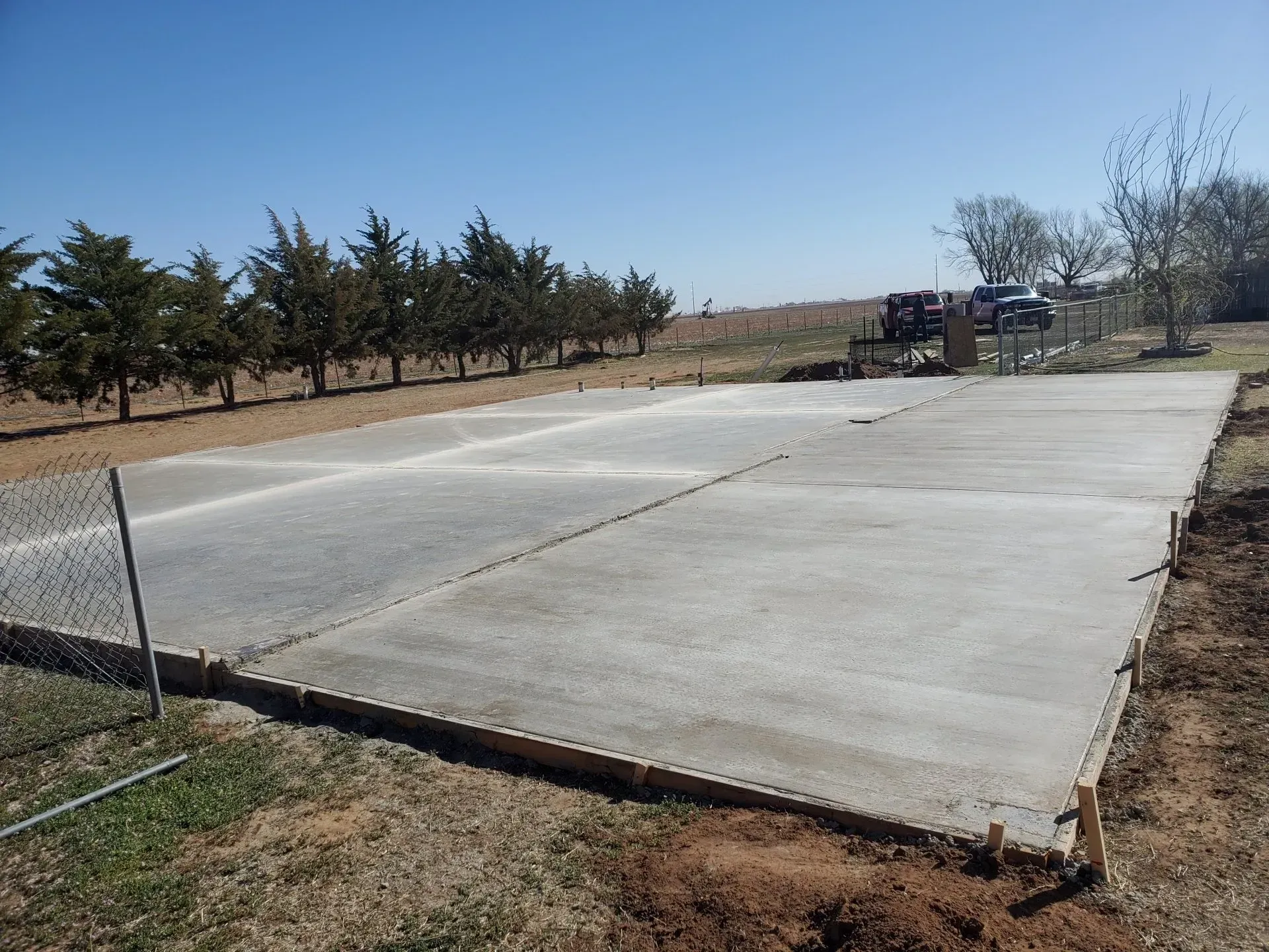 Large concrete slab under construction in a rural area with trees and a truck in the background