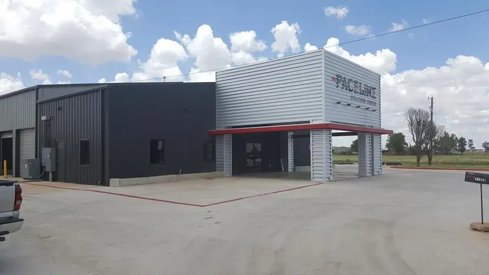 Modern gray commercial building with red awning and large windows under a cloudy sky
