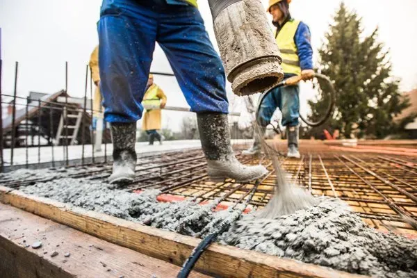 Construction workers pouring concrete onto rebar at a building site
