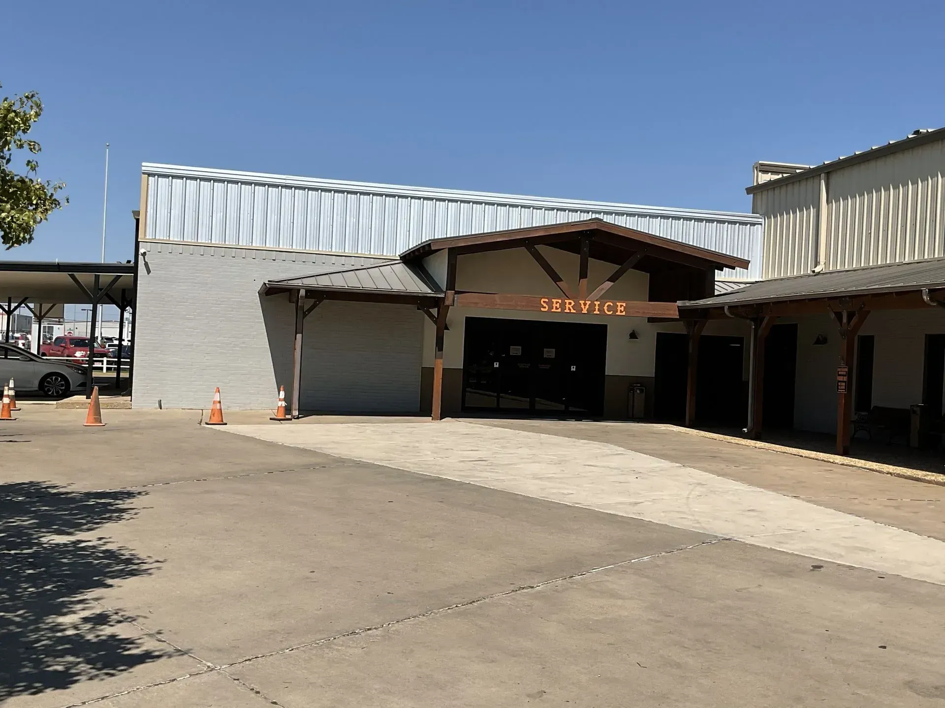 Exterior of a warehouse-style building with open garage bays and a concrete driveway under a clear blue sky