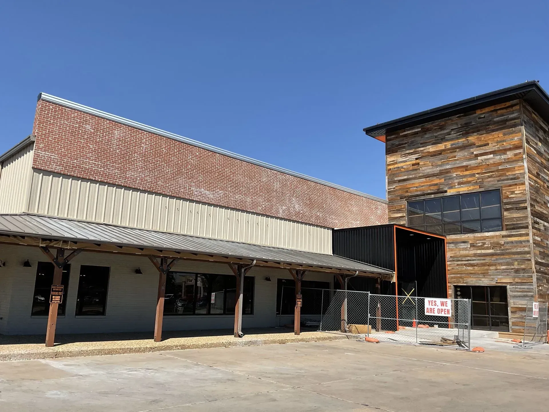 Old rustic buildings with metal roofs and a wooden facade under a clear blue sky