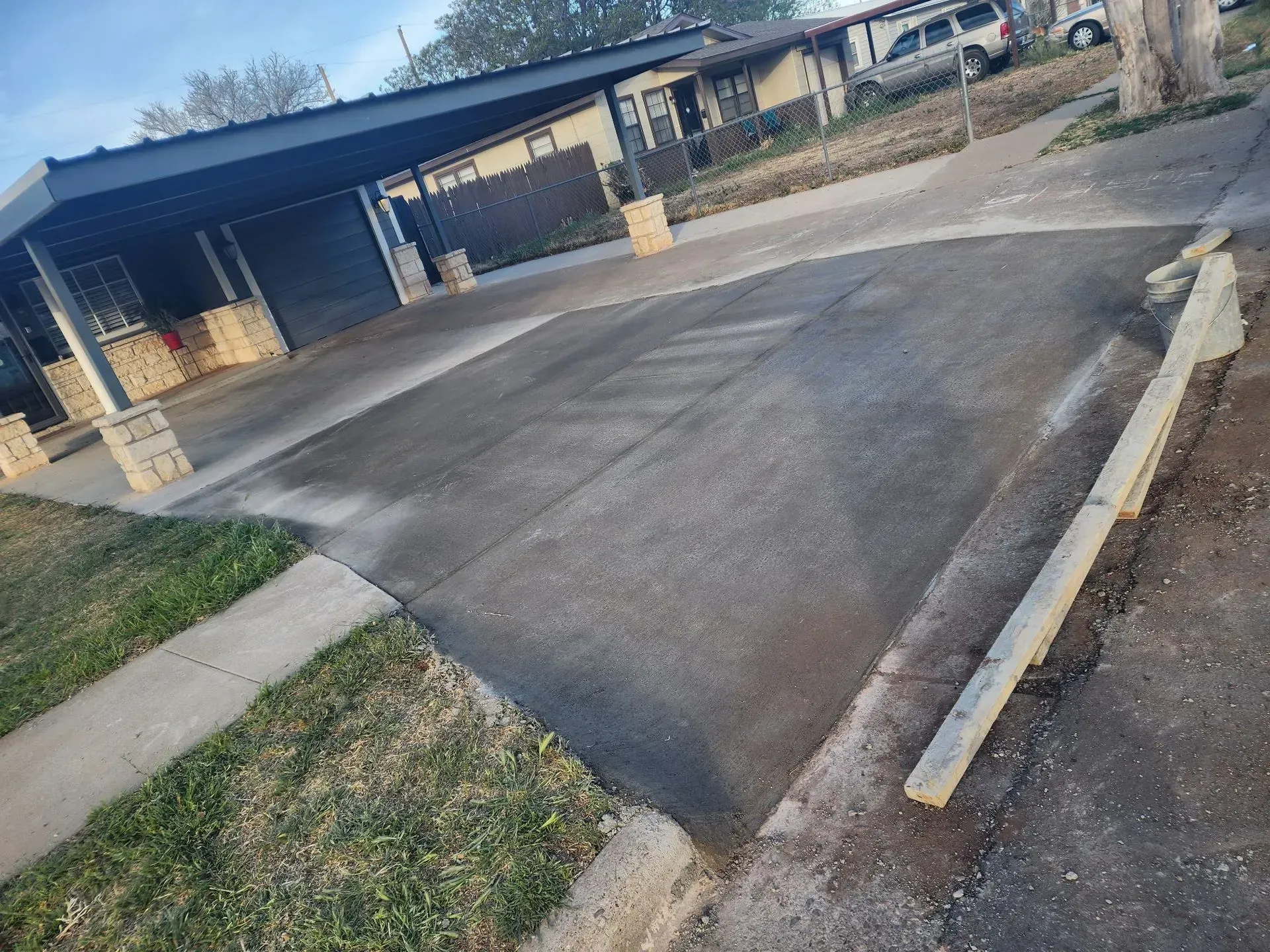 A tilted view of an apartment parking lot with a raised curb and driveway entrance.
