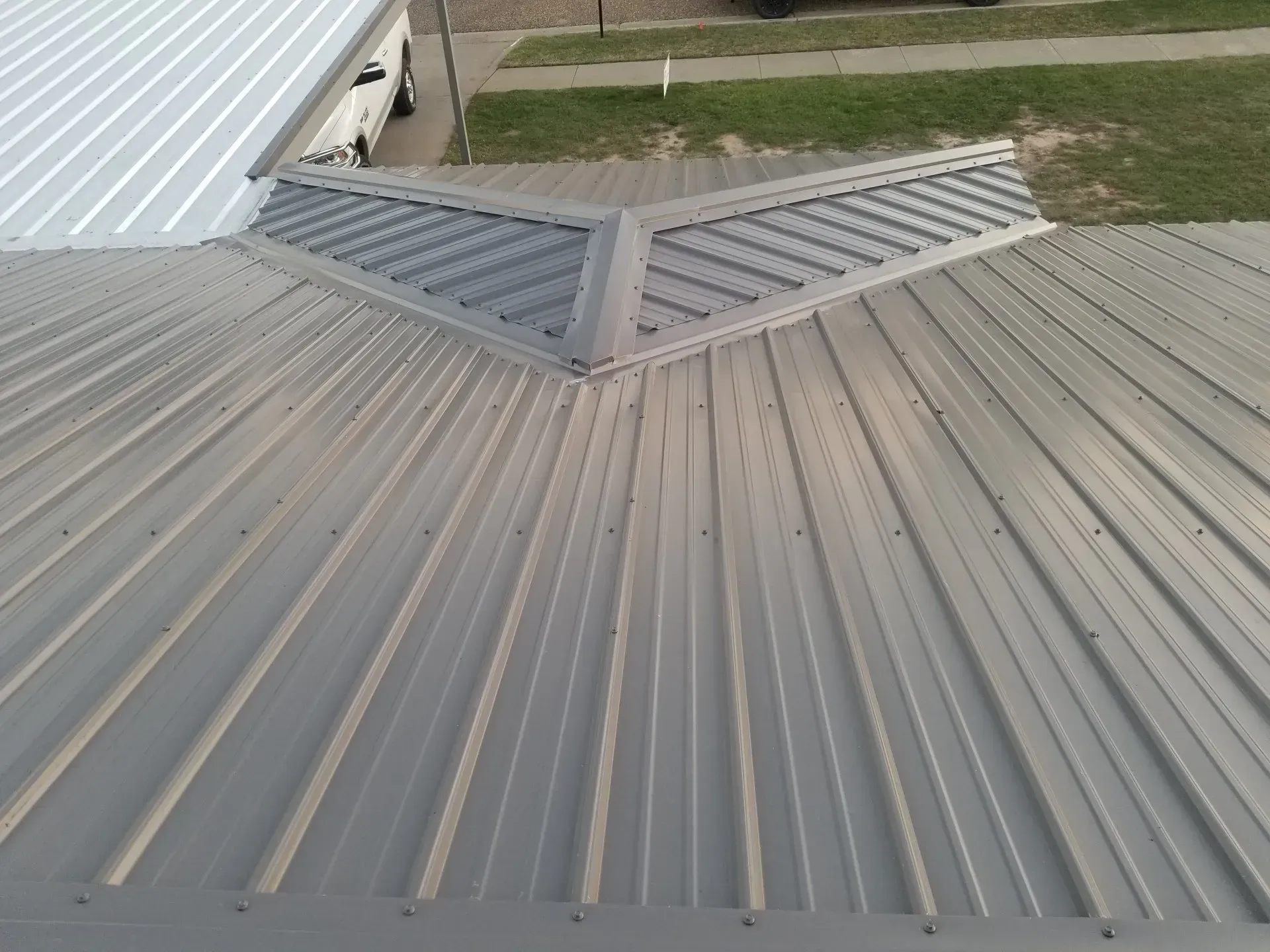 Aerial view of a corrugated metal roof with a central vented ridge and adjacent roof sections