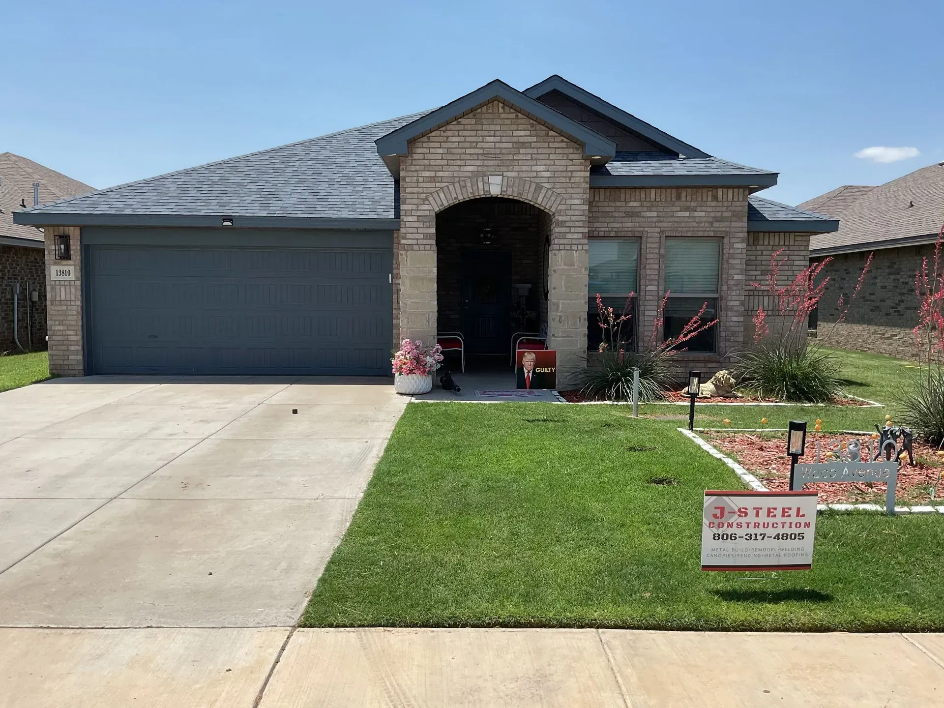 Suburban brick house with gray garage, driveway, and a manicured lawn in front.