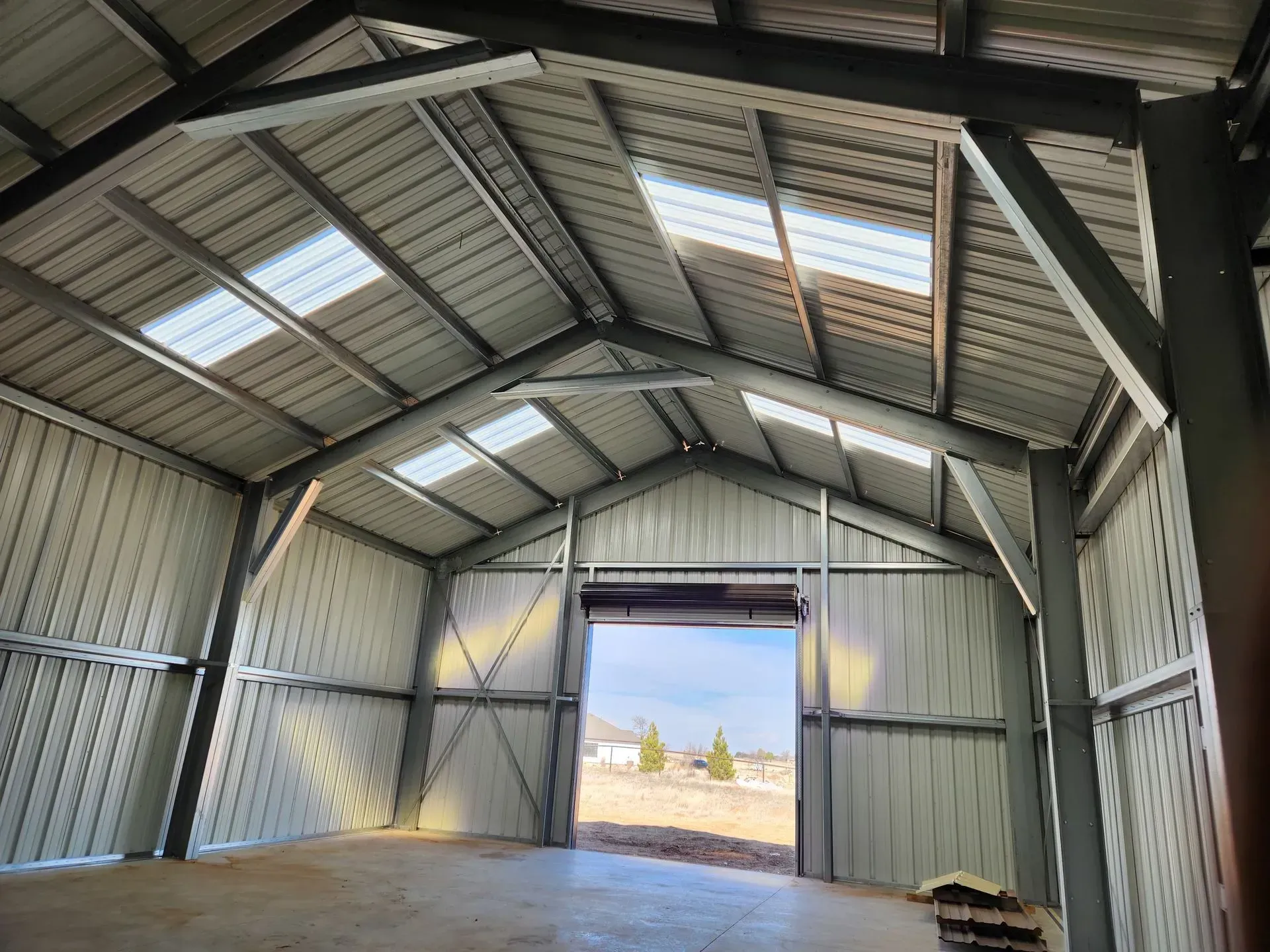 Interior of a metal shed with open doorway, showing bright daylight outside.