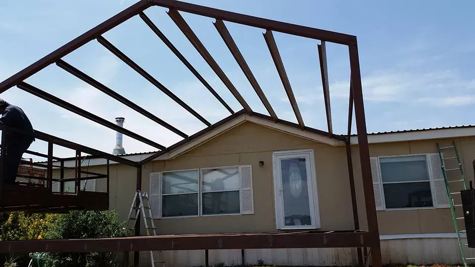 House with a partially built metal patio frame in the front yard