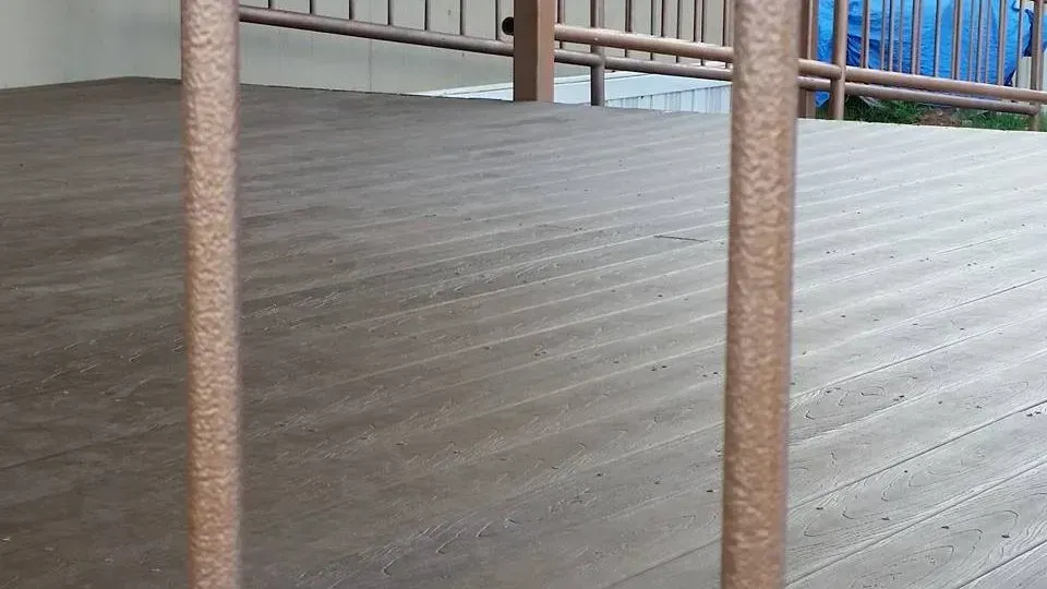 Wooden deck floor with two vertical rust-colored posts and a railing in the background.