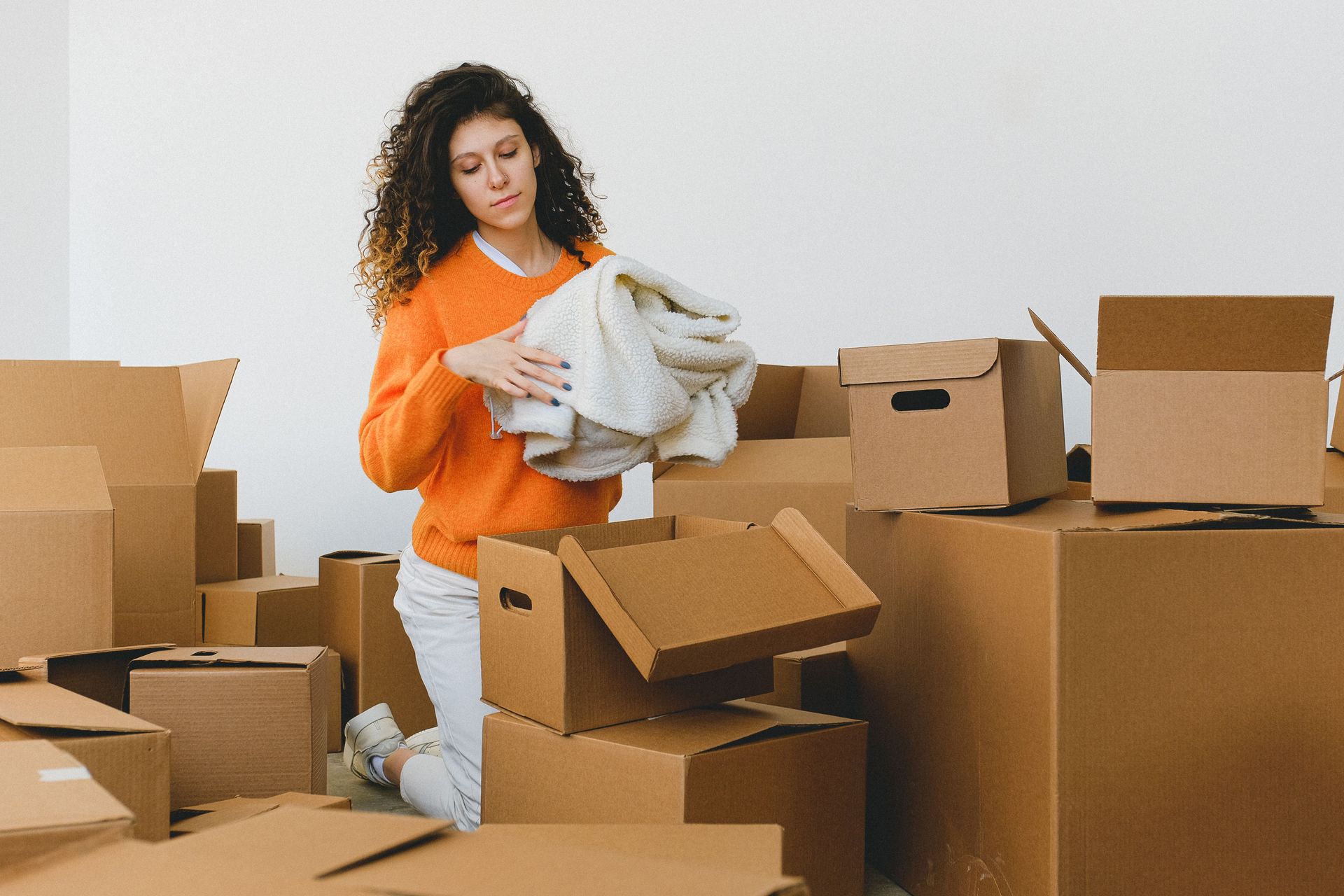 Woman and child kneeling, unpacking belongings from boxes.