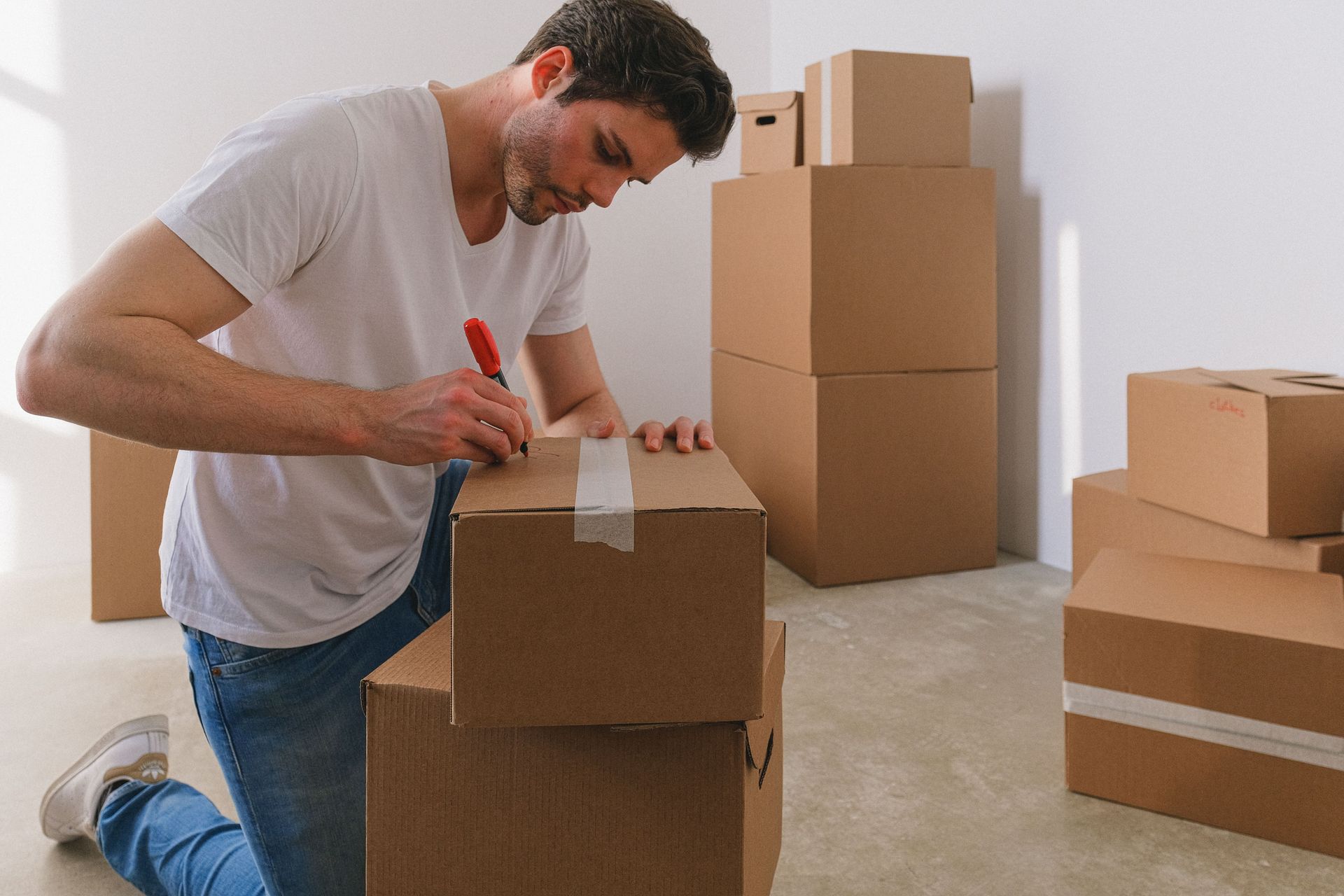 Woman and child kneeling, unpacking belongings from boxes.