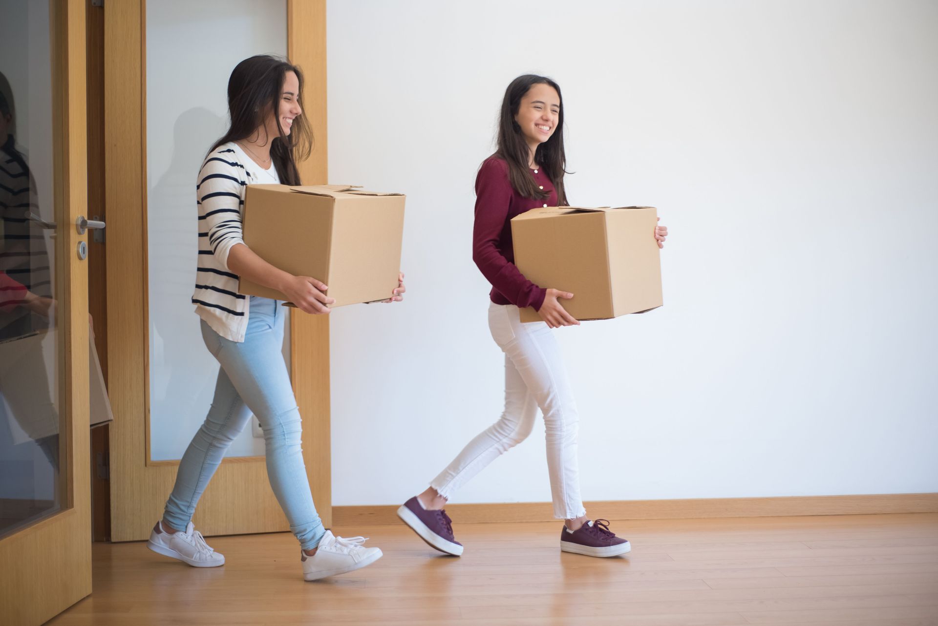 Woman and child kneeling, unpacking belongings from boxes.