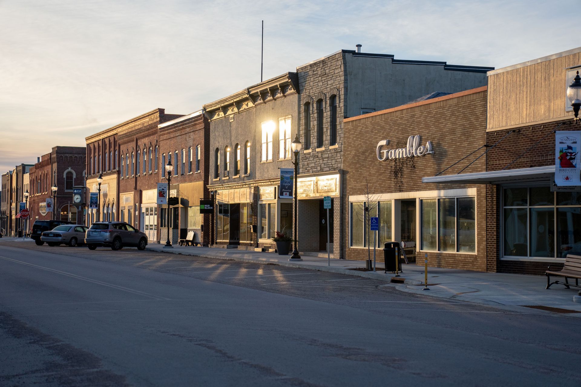 A row of brick storefronts along a street in evening light.
