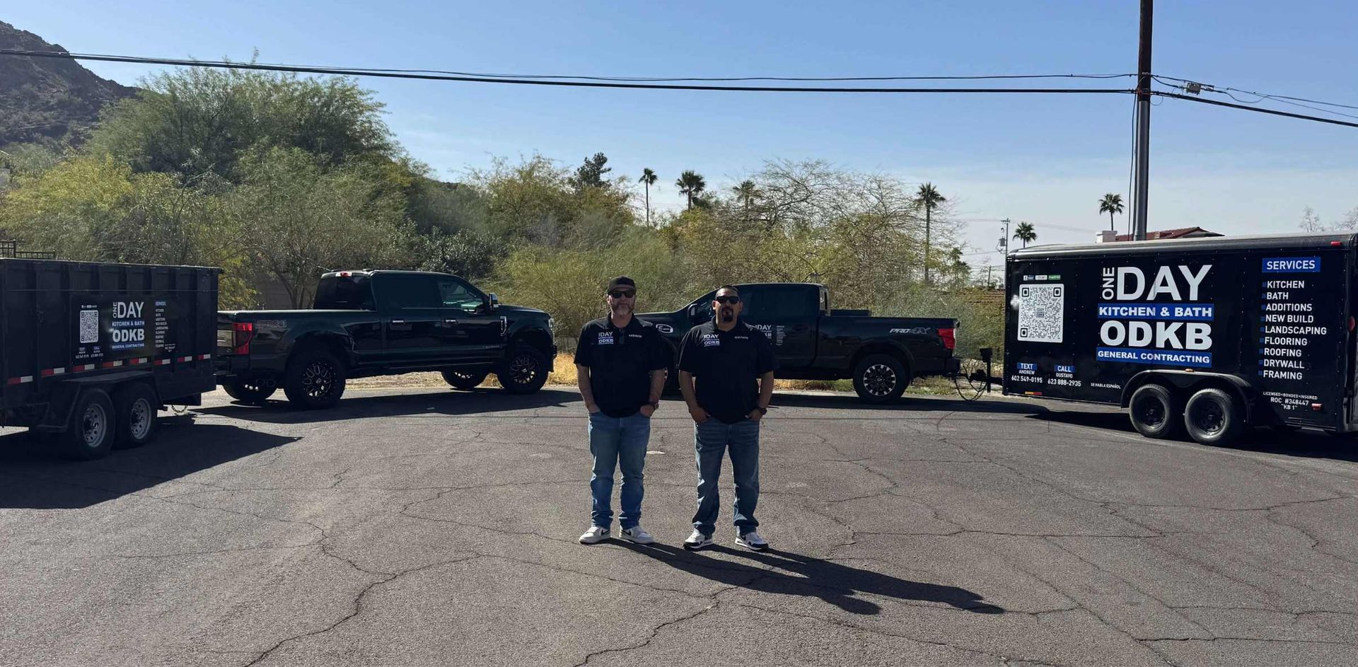 Two contractors with black pickup trucks and work trailers branded with