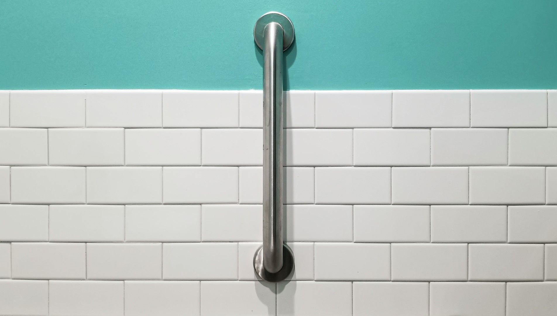 Close-up of a stainless steel grab bar on white tile for safer kitchen and bathroom remodeling in Avondale, AZ