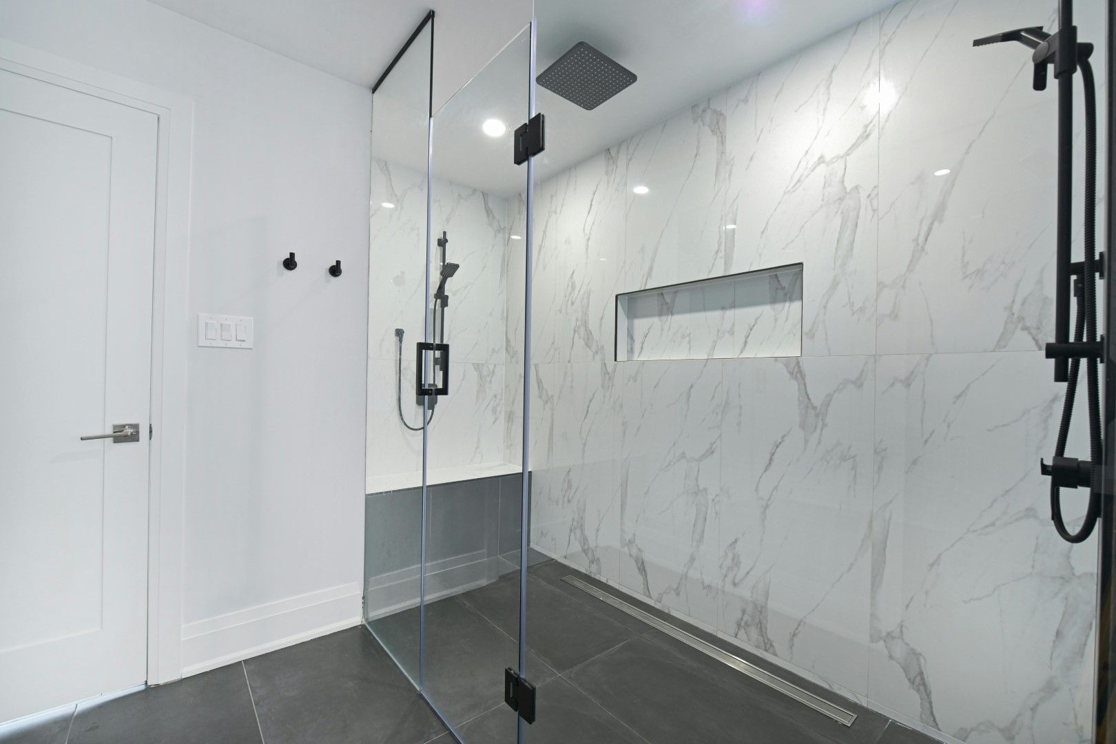 Walk-in shower with marble-style tile walls and black fixtures after kitchen and bathroom remodeling in Avondale, AZ
