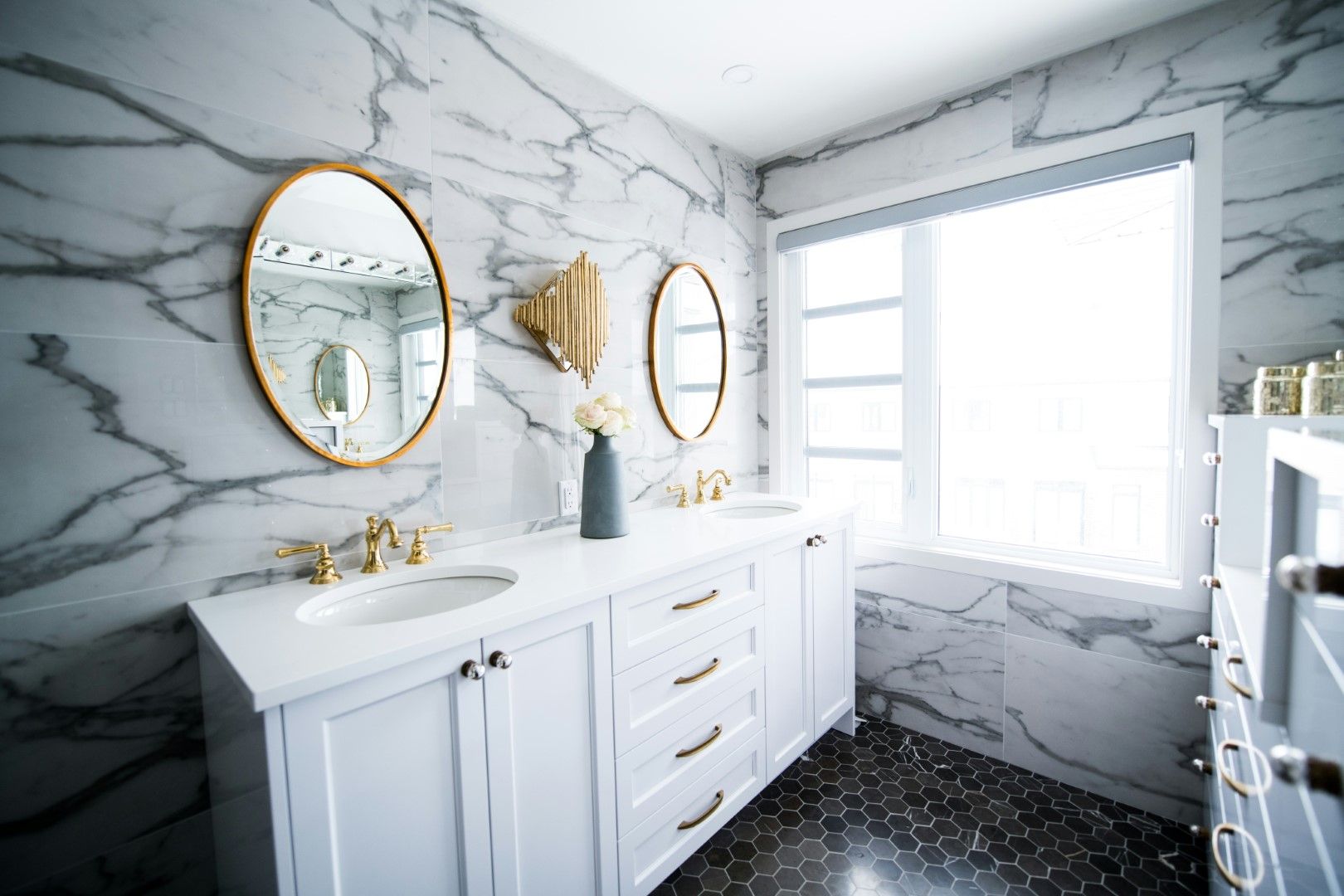 White bathroom vanity with round mirrors and marble-style wall tile after kitchen and bathroom remodeling in Avondale, A